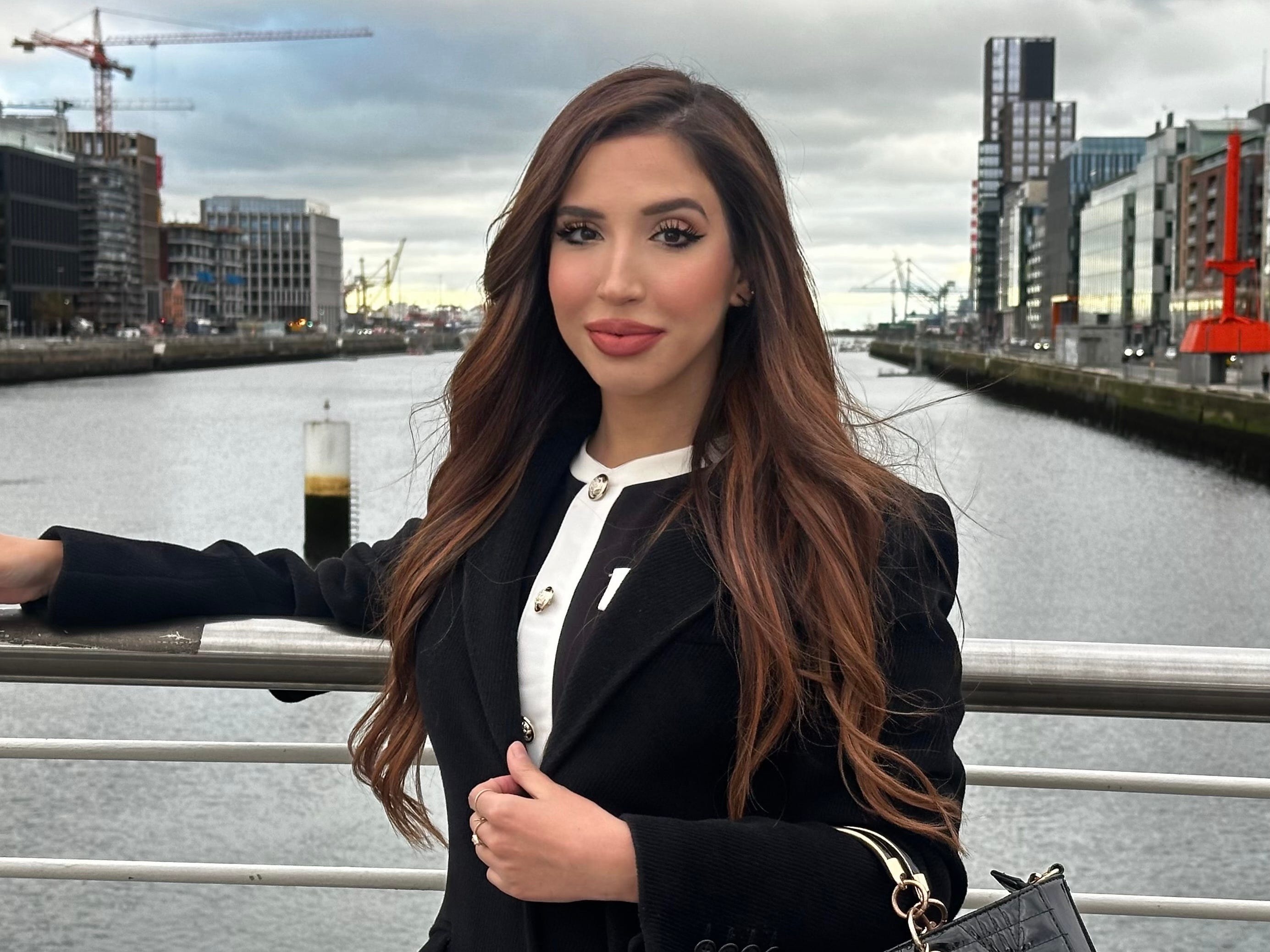 a woman in a black outfit poses on a bridge