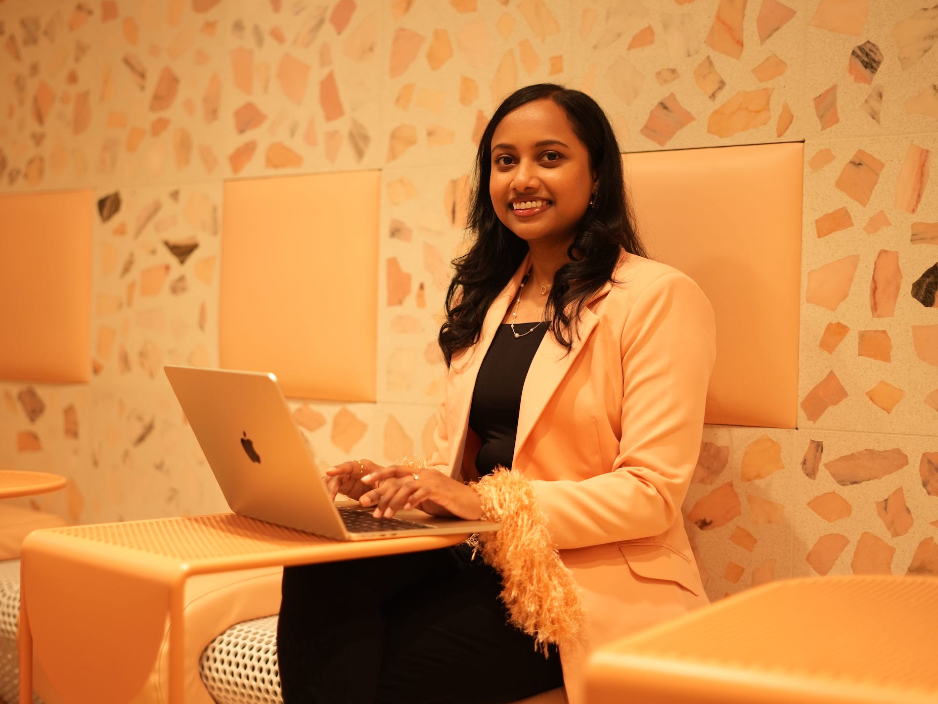 a woman poses for a photo while sitting at a laptop