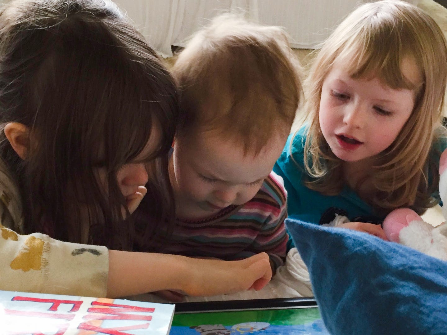 The author's three kids, lying on the ground and reading together.