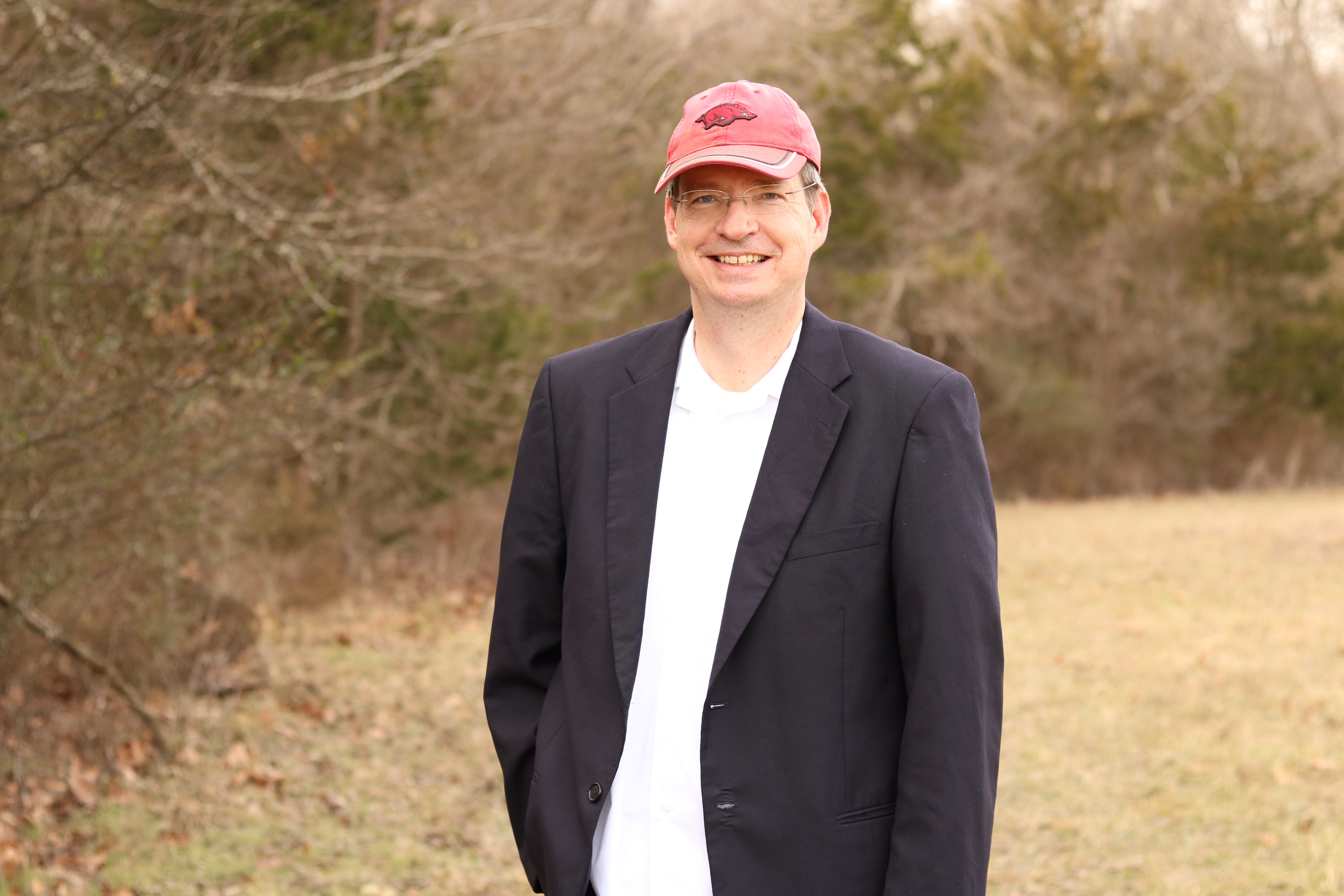Walter Green standing outdoors with a blazer and red baseball cap.