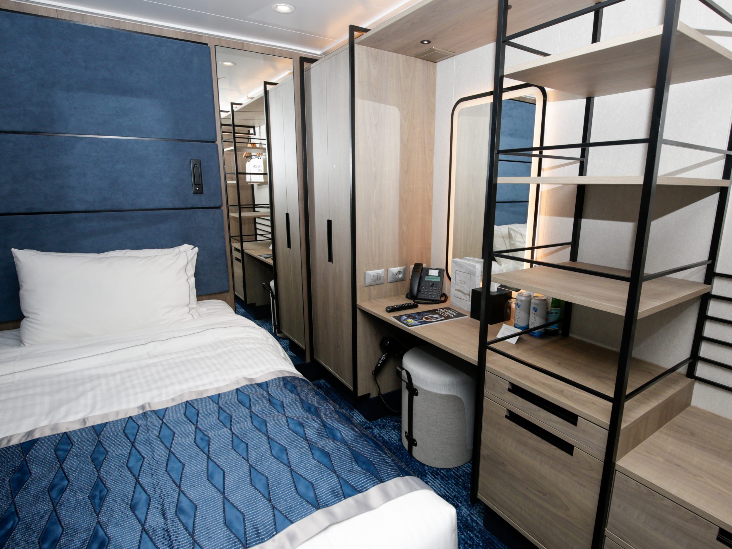 bed, storage, and shelving in a single-person studio cabin on Norwegian Aqua