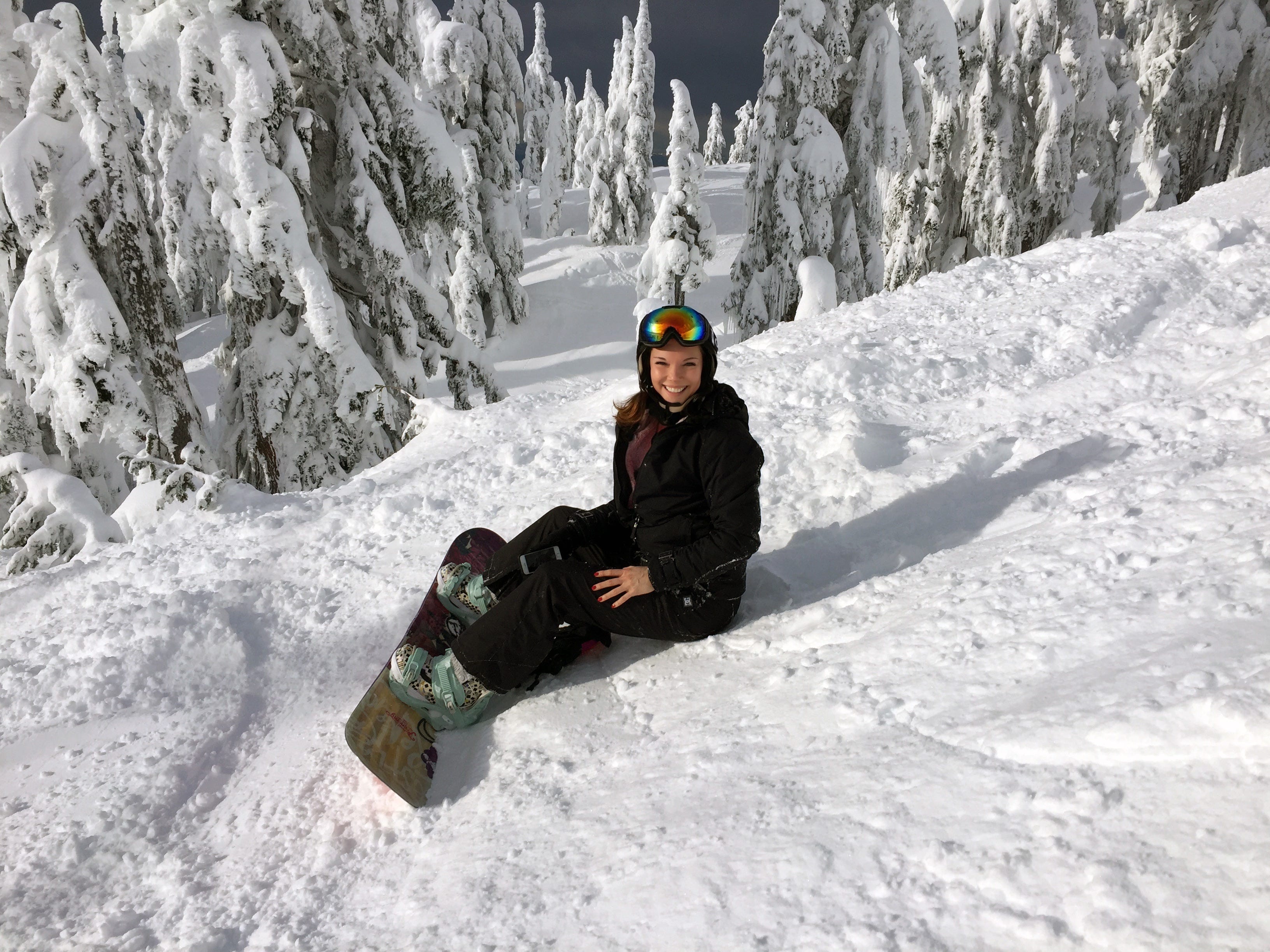 Kathryn Anderson in black snow gear snowboarding on a mountain
