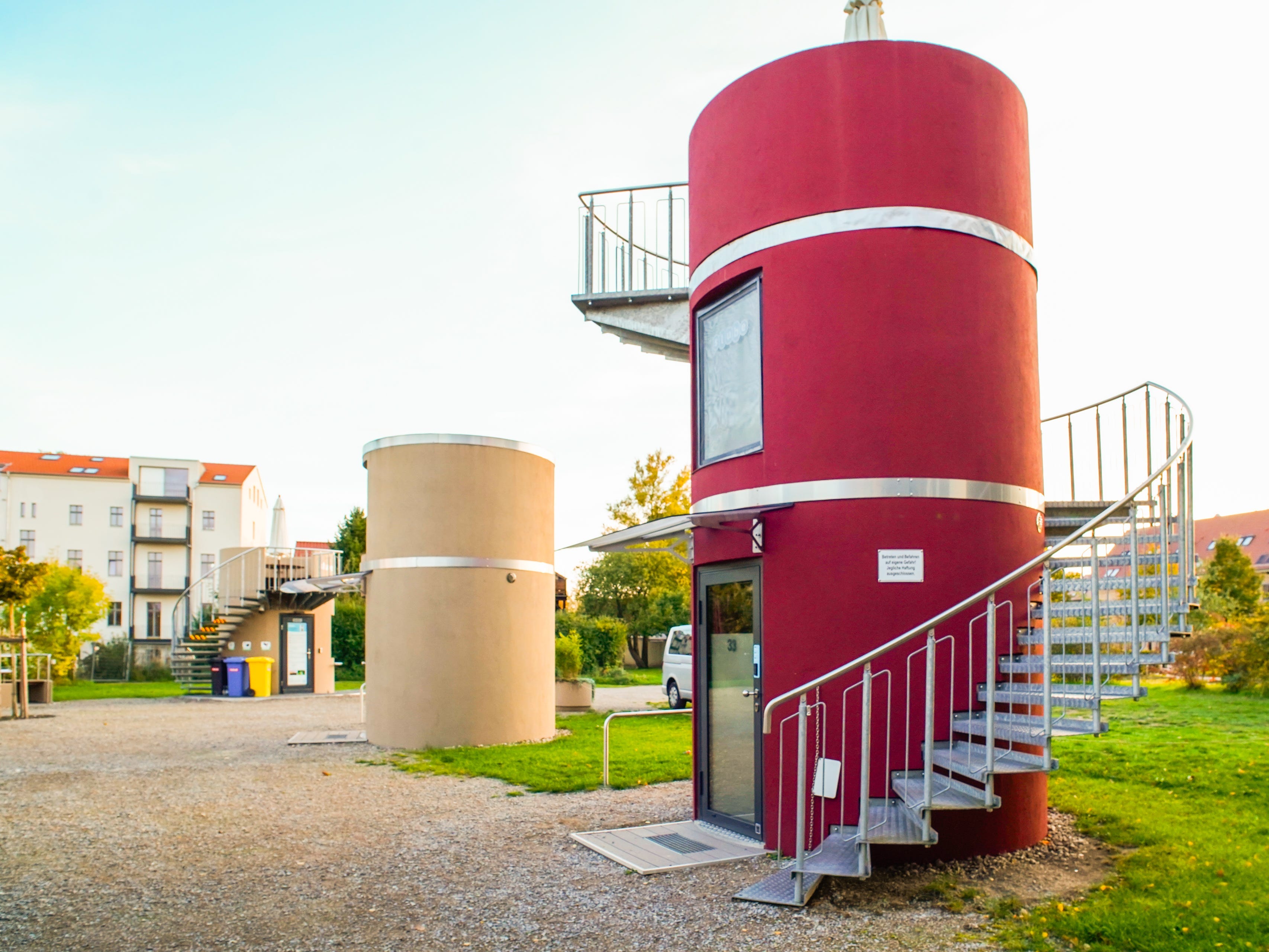 Cylindrical homes on a flat property with buildings in the background