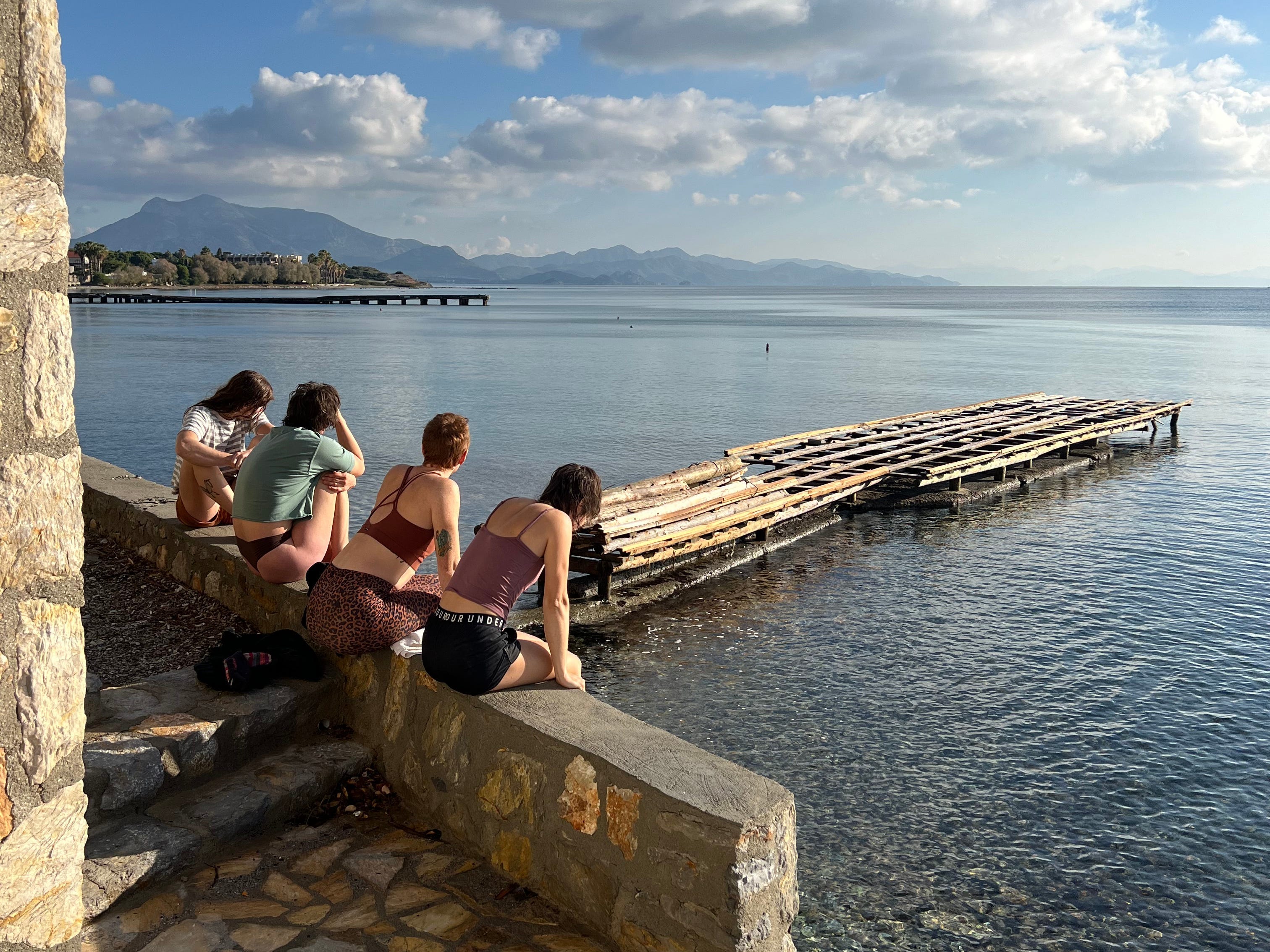 Group of women sitting on stone wall in Turkey staring out into water
