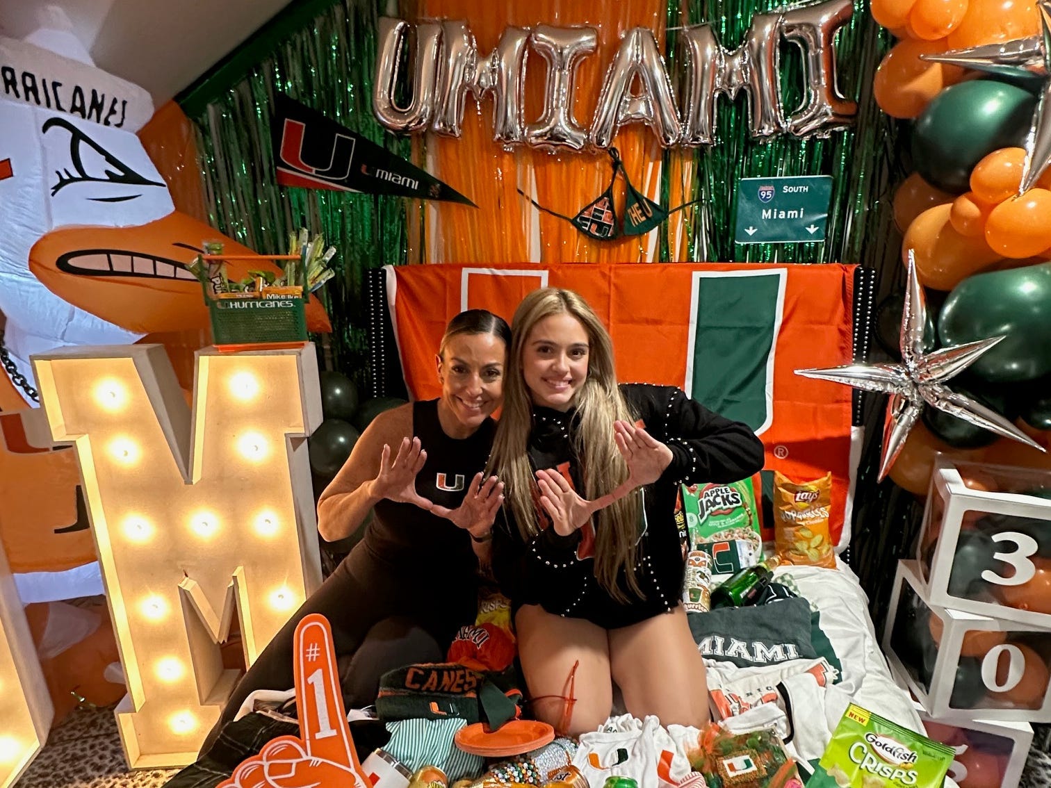 Melinda and Sienna Long posing with University of Miami colors and decor for the college bed party.