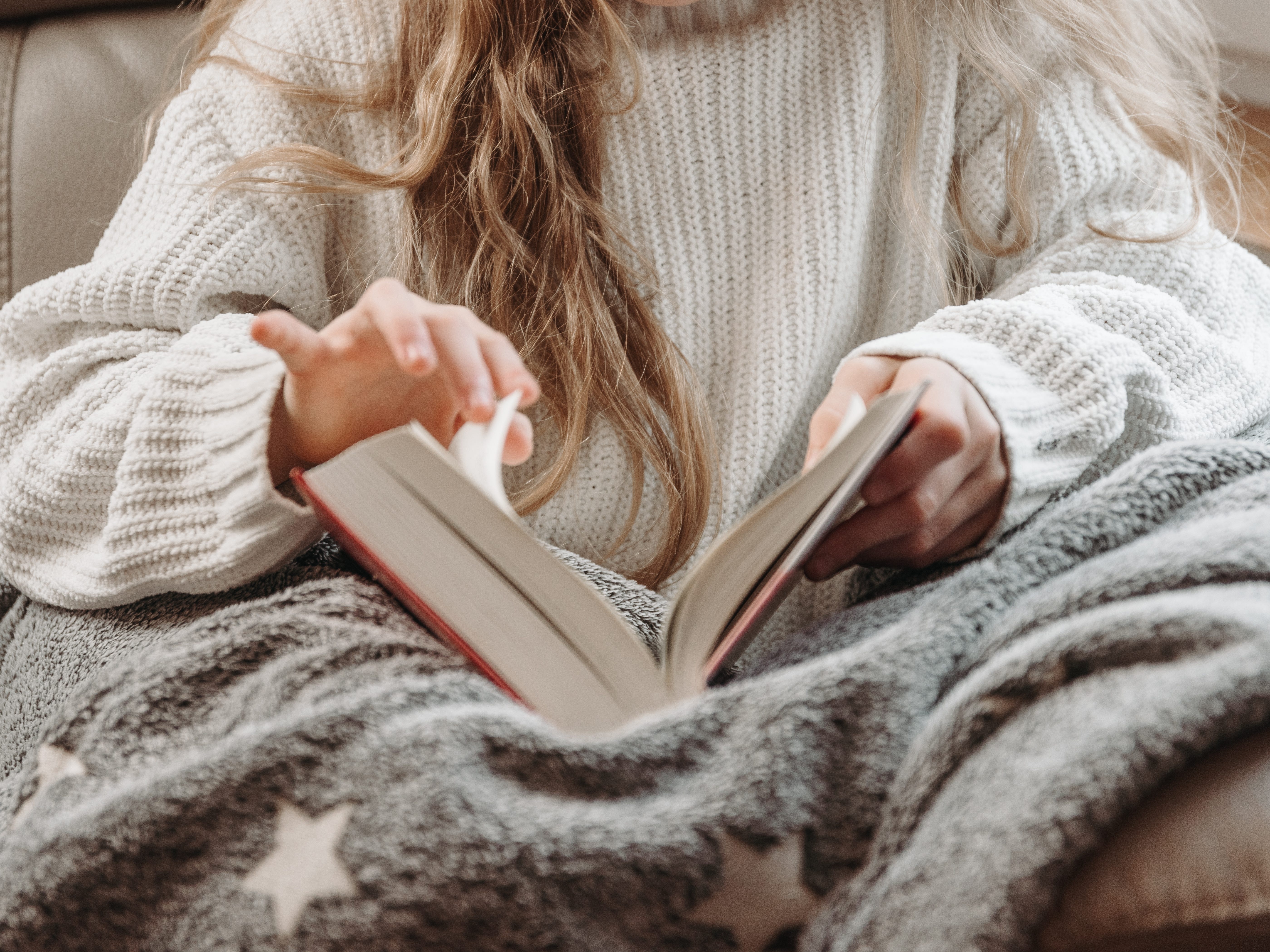 A close-up of a young woman flipping the page of a book.