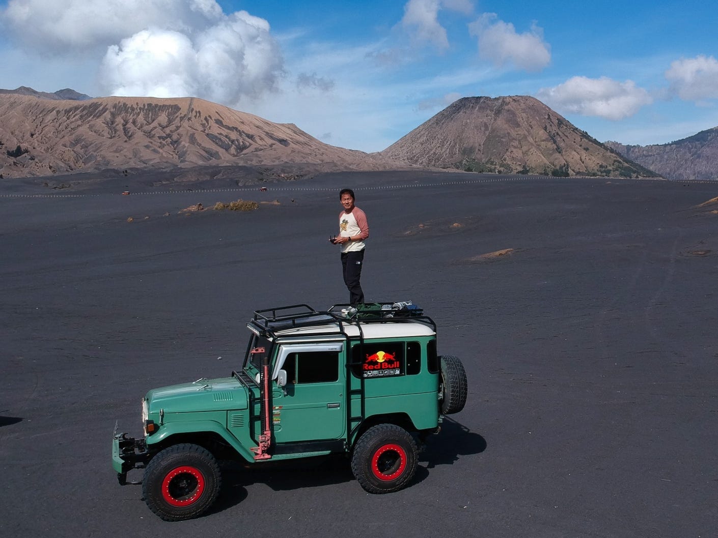 A man is standing on a green off-road vehicle in Indonesia.