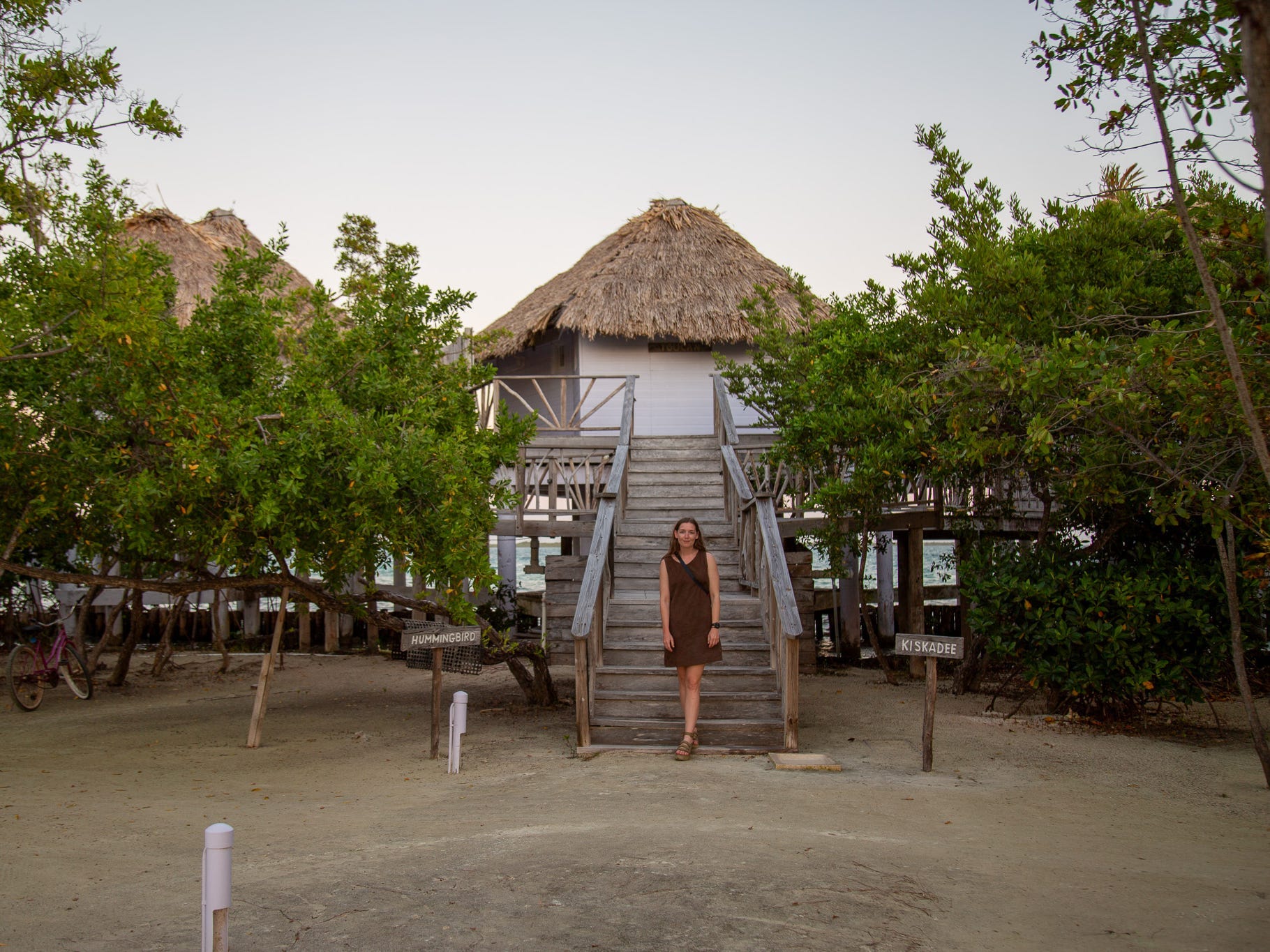 The author stands in front of bungalows at the Thatch Caye resort in Belize.