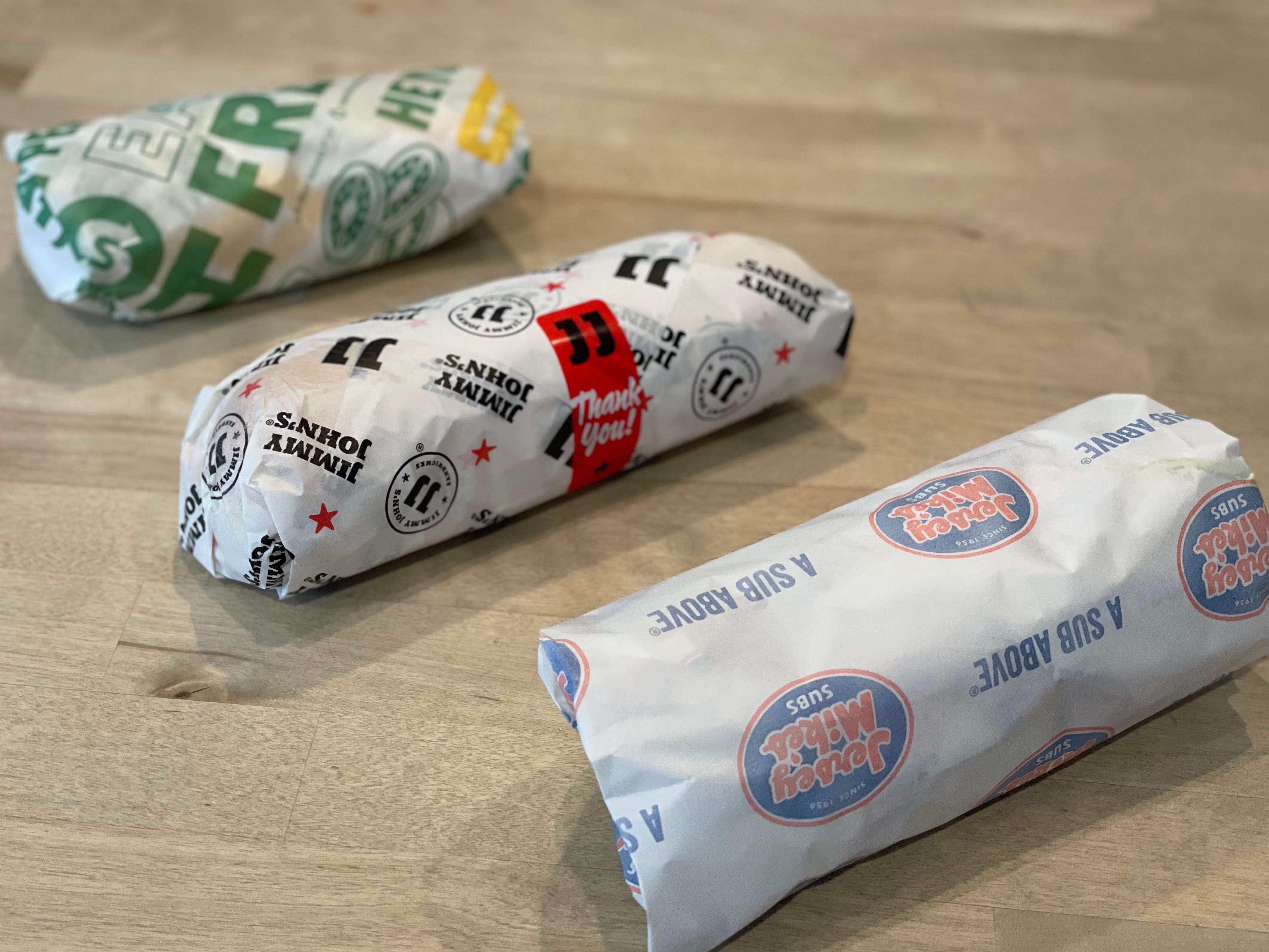Three wrapped subs from Subway, Jimmy John's, and Jersey Mike's.