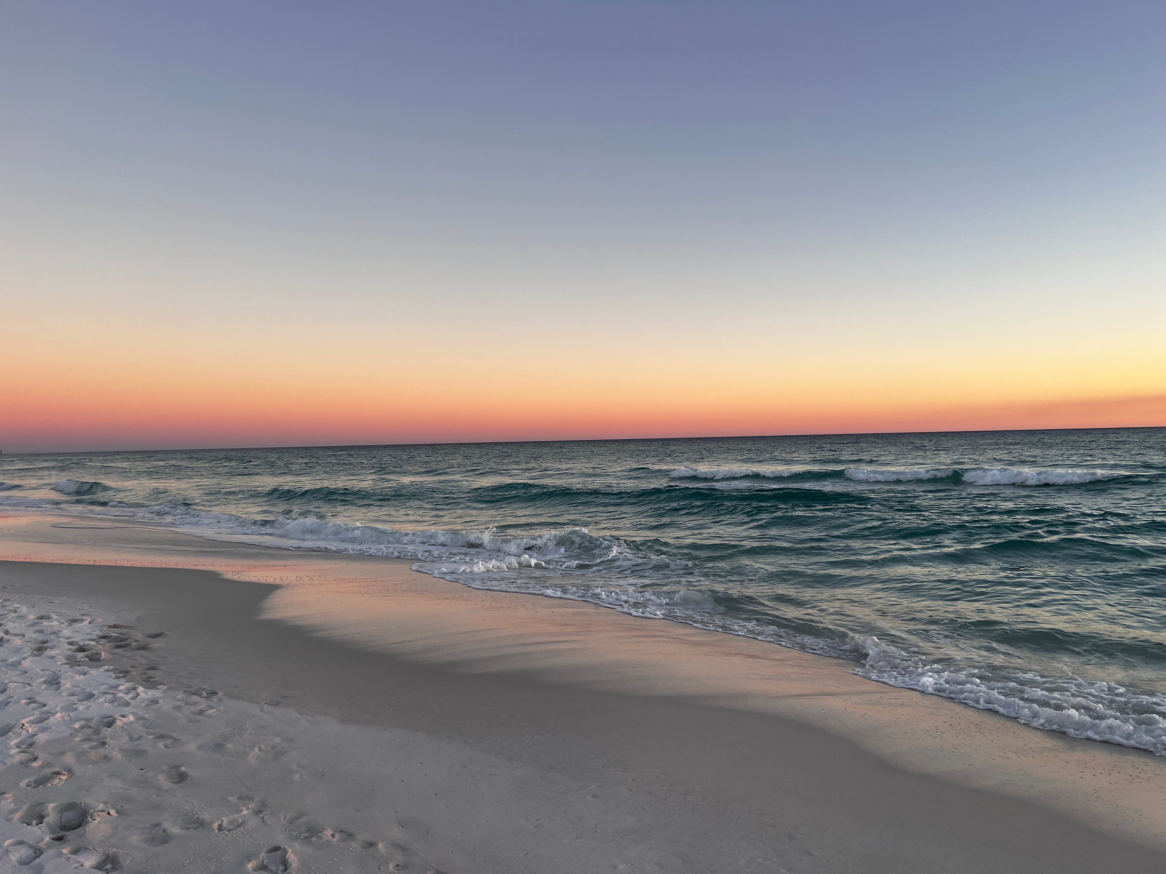 The sunset over the ocean on an empty beach.