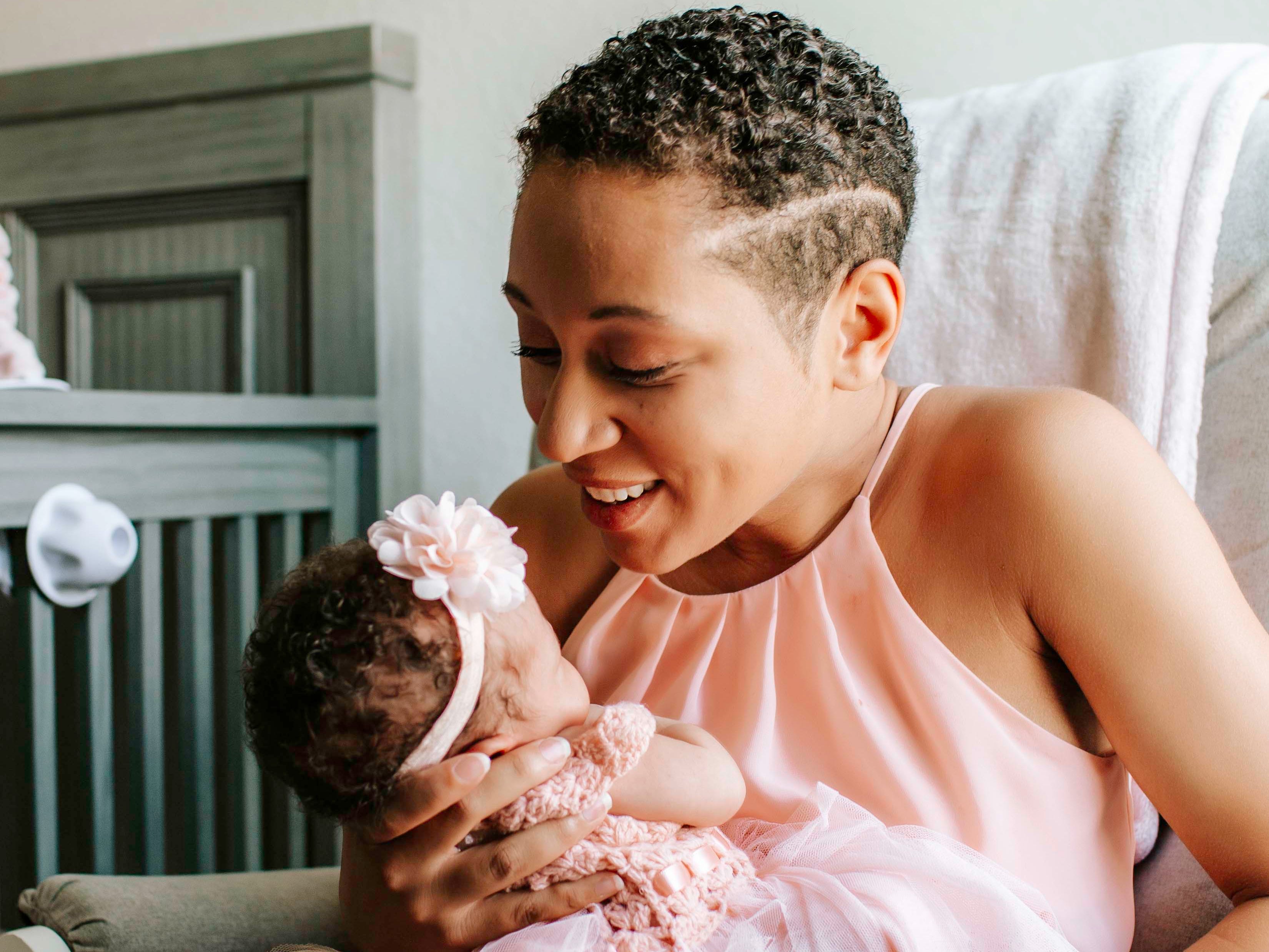 The author in a chair with her daughter when she was a newborn, both wearing pink.