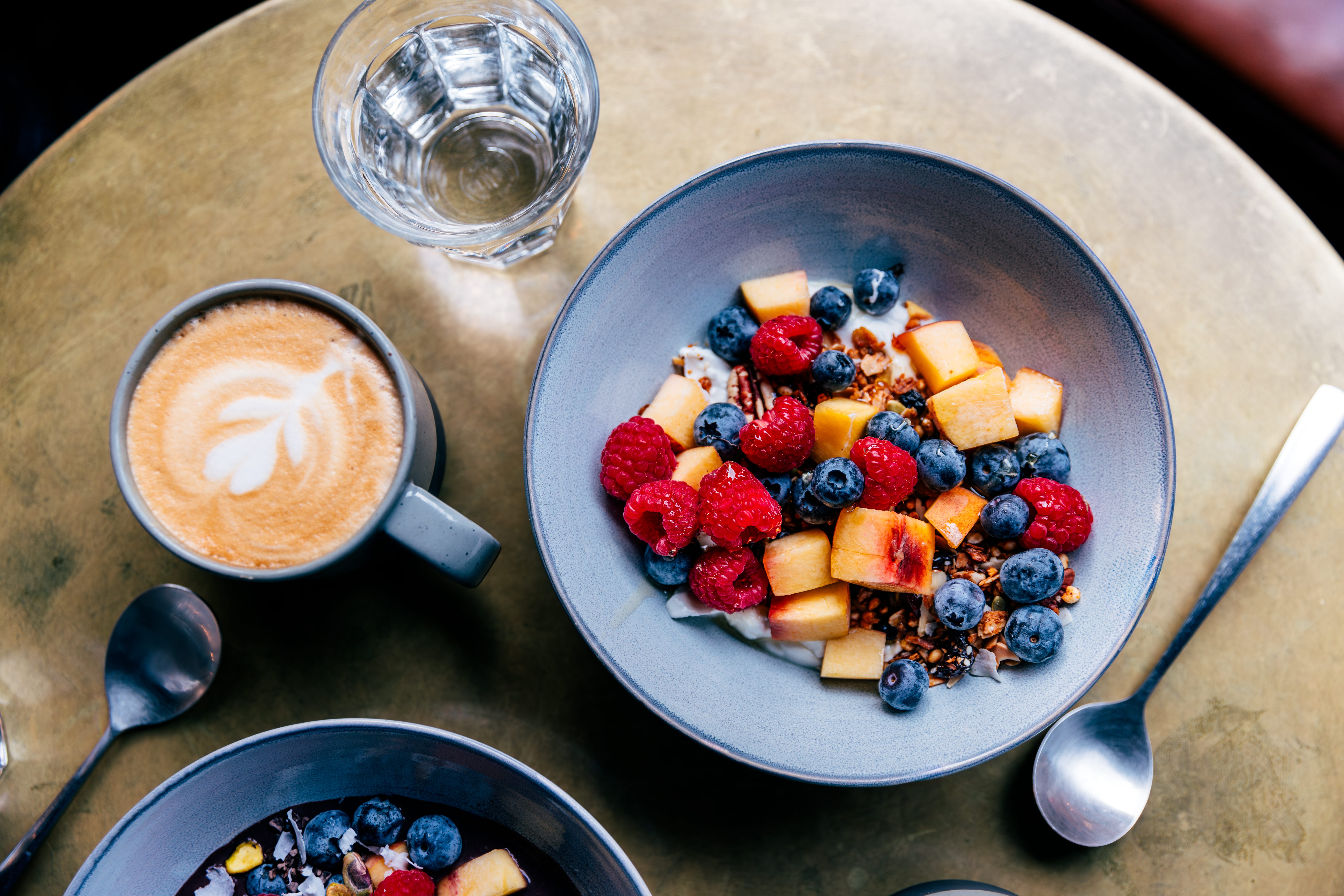 Coffee, water, and a bowl of yoghurt, fruit and granola.