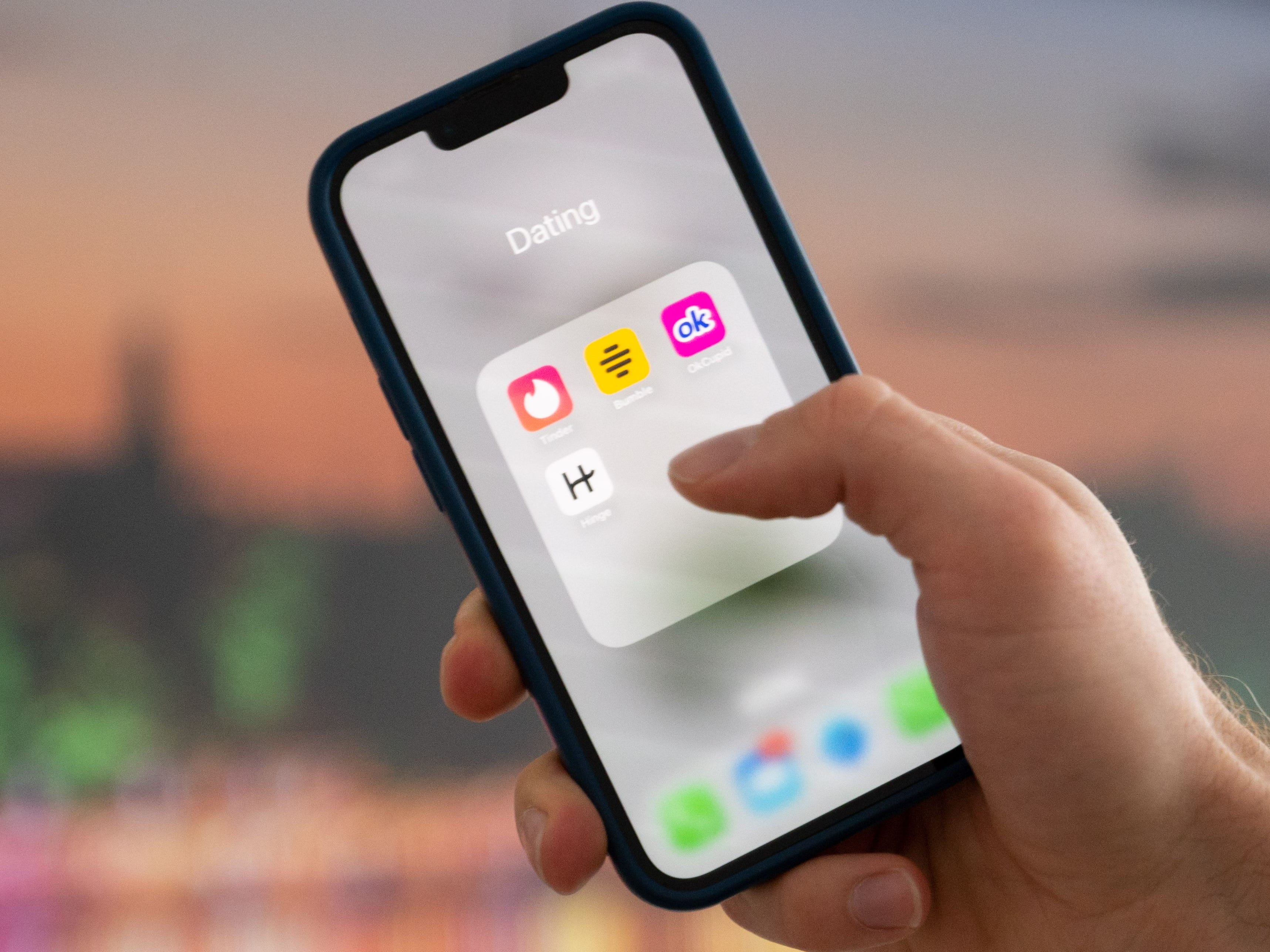 a hand holding a phone with dating app on the screen