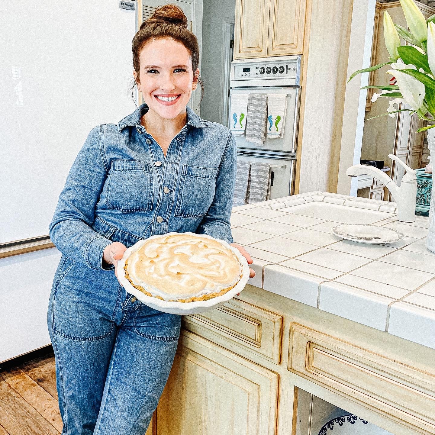 Leslie Garetto standing in a kitchen holding a pie and smiling for the camera