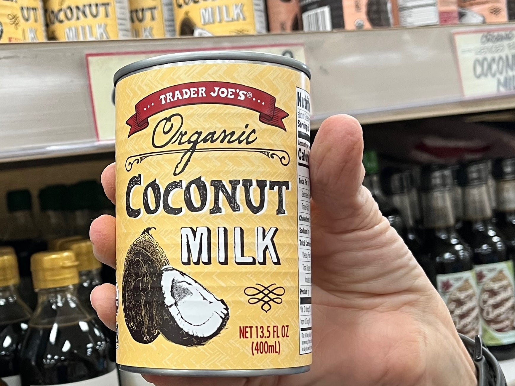 Hand holding Trader Joe's organic coconut milk in store