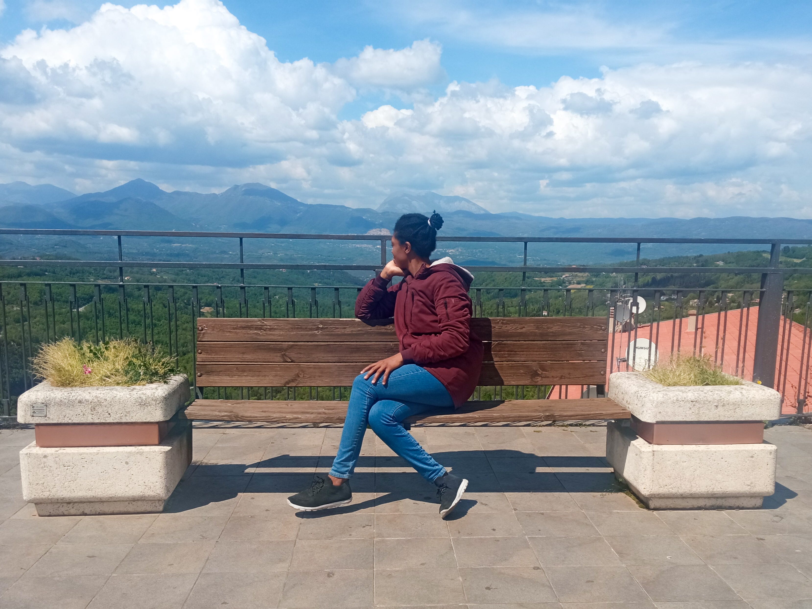 The author posing on a bench looking at the view of mountains in Italy.