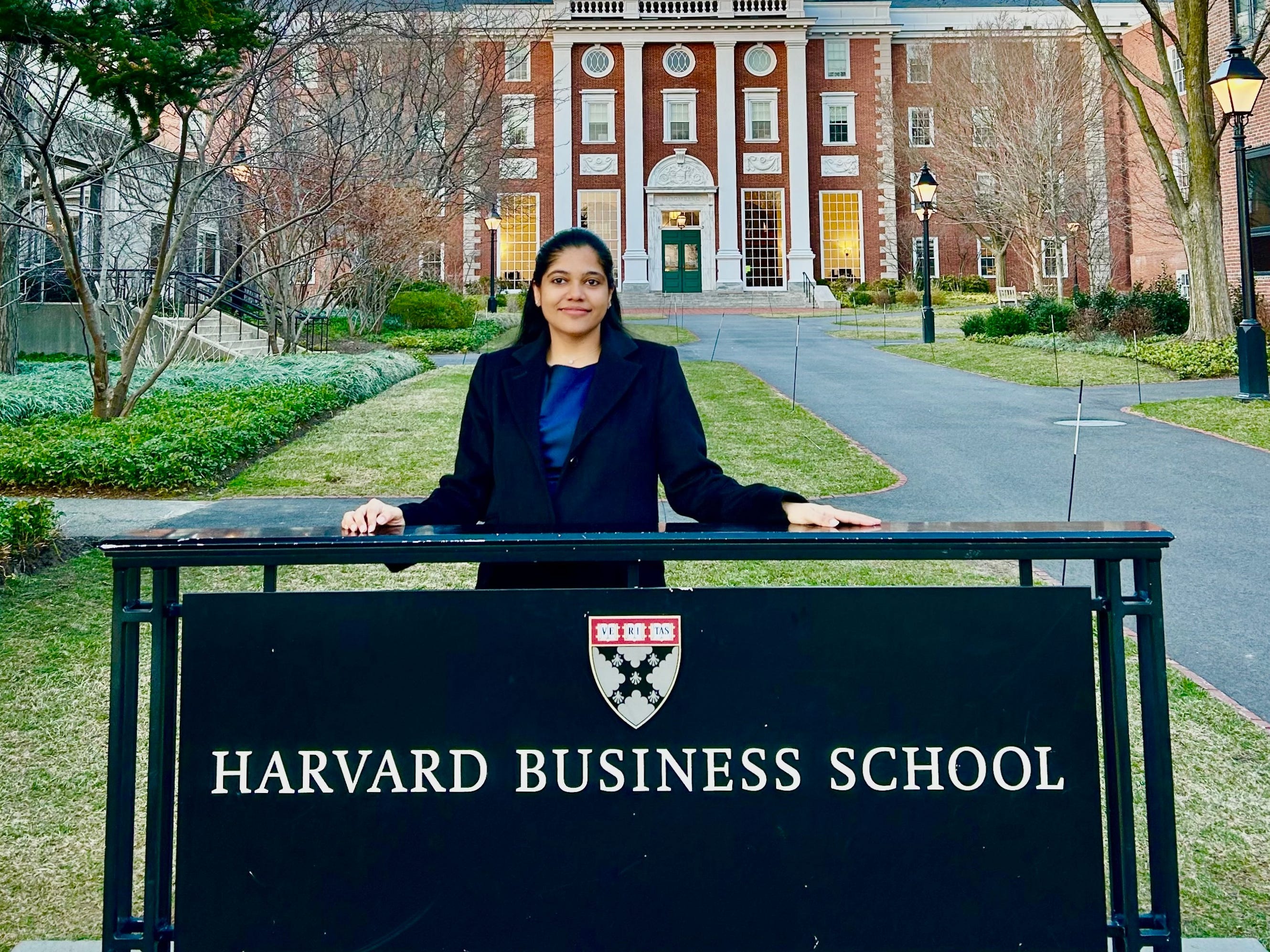 Shreya Mishra Reddy in front of the Harvard Business School sign.
