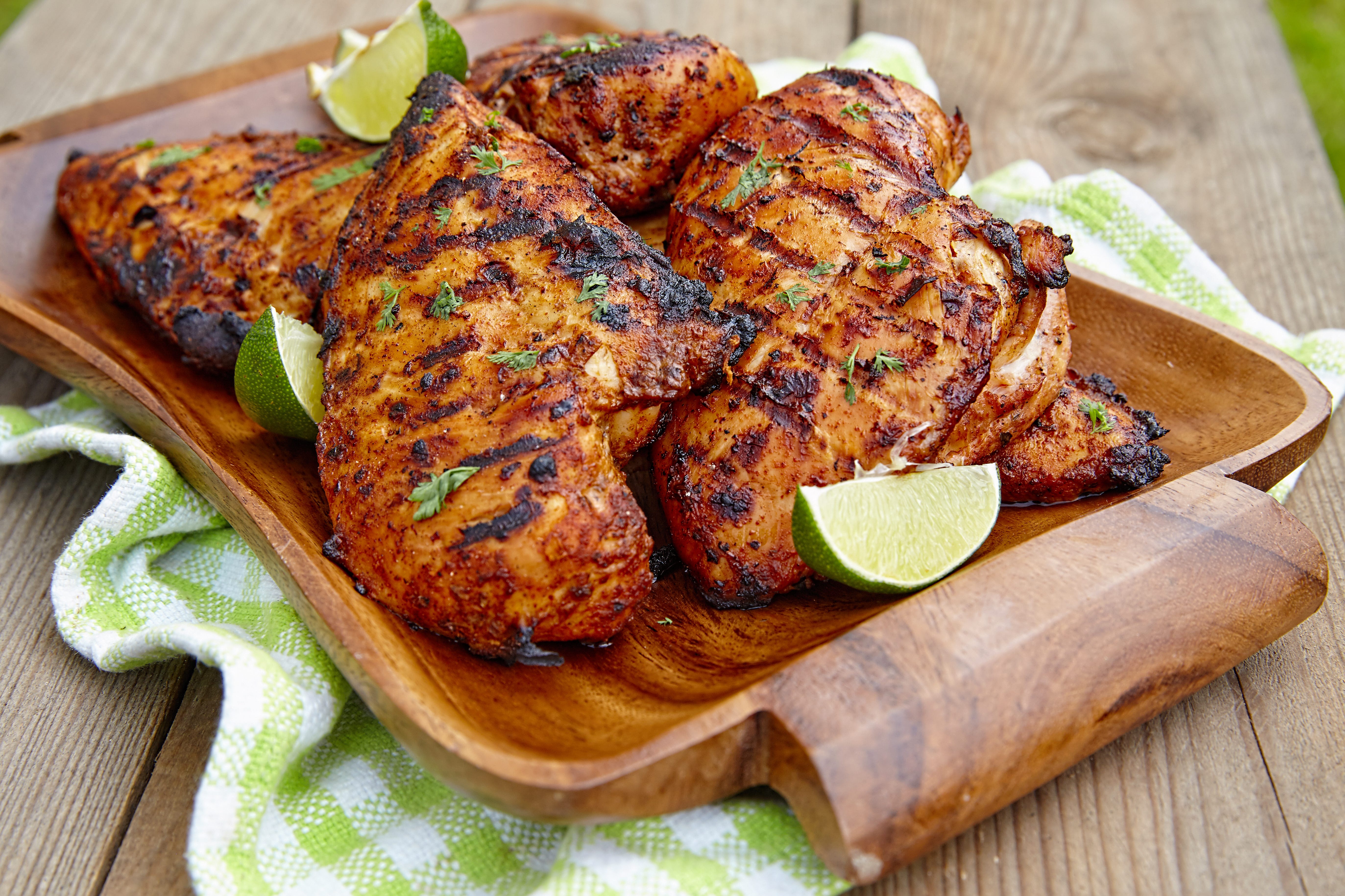 grilled chicken on wood tray with limes