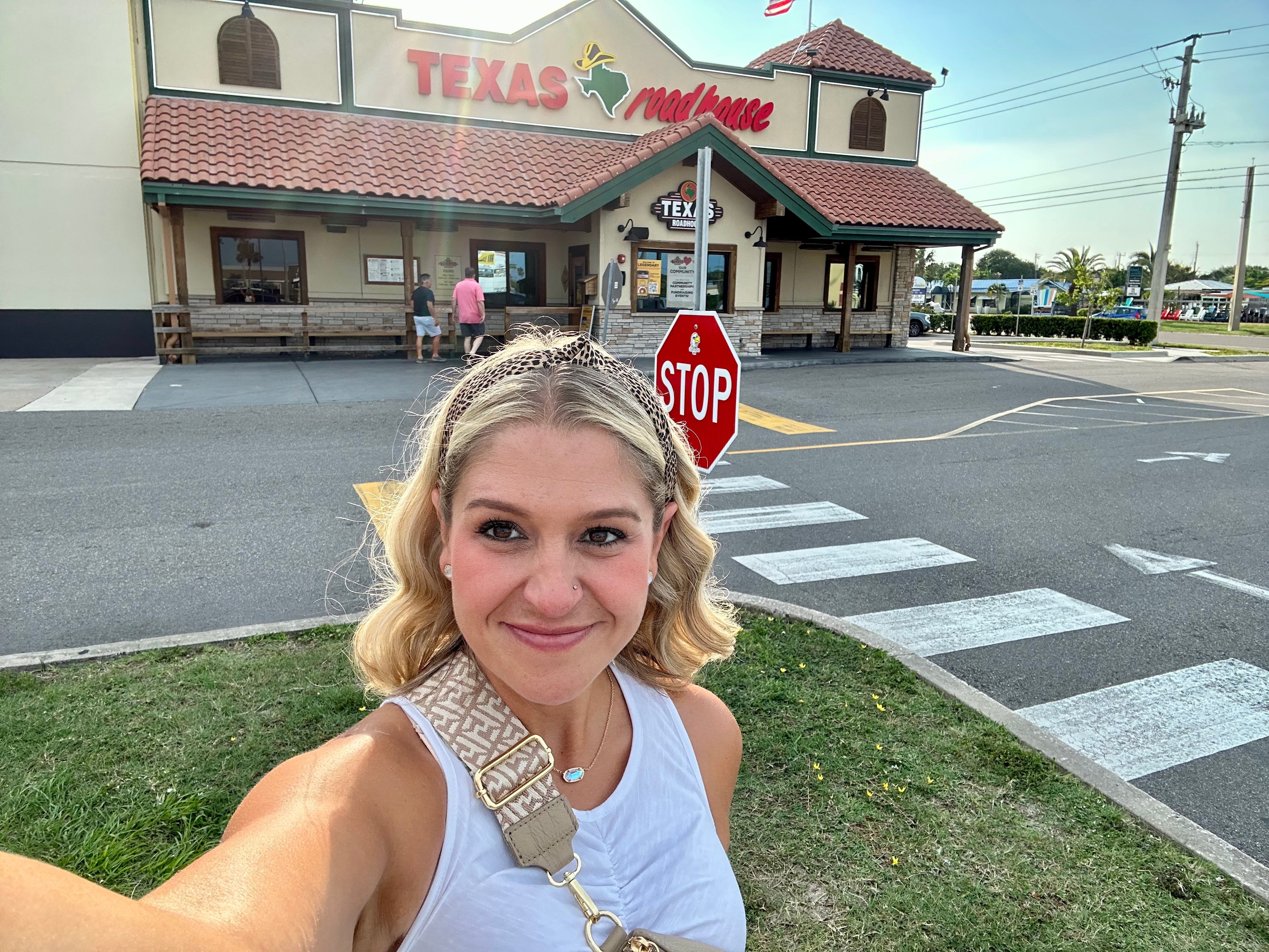 A woman taking a selfie and smiling outside a Texas Roadhouse.
