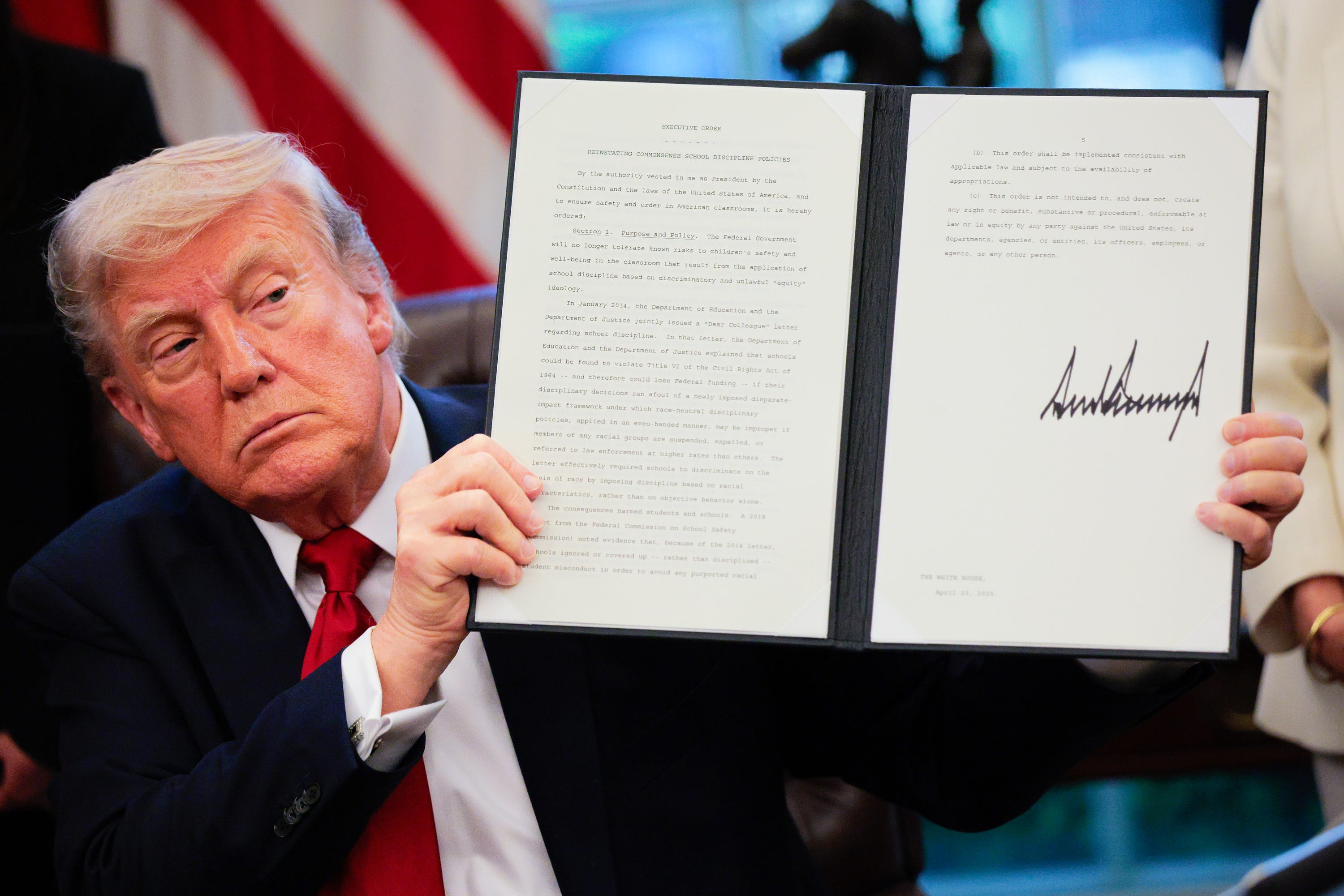 Donald Trump holding up an executive order with his signature on it.