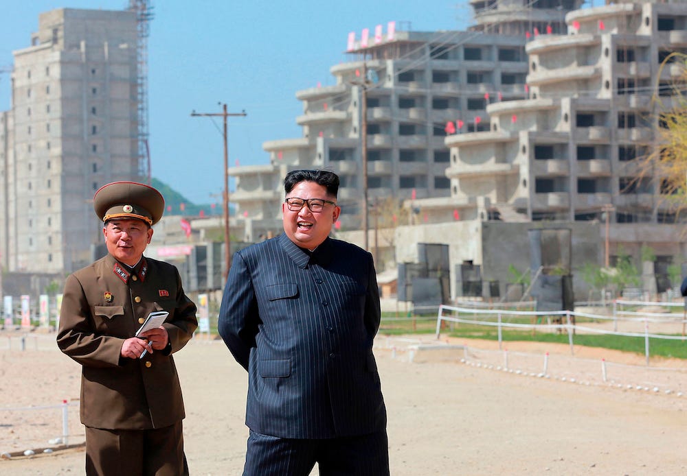 A smiling Kim Jong Un and an official inspect the construction site of the Wonsan-Kalma coastal tourist area in Gangwon-do, North Korea, showing tourist buildings under construction in the background, in this image shared by state media.