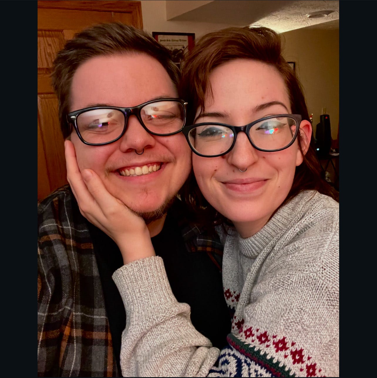 A married queer couple take a photo while one person cradles the other person's head.