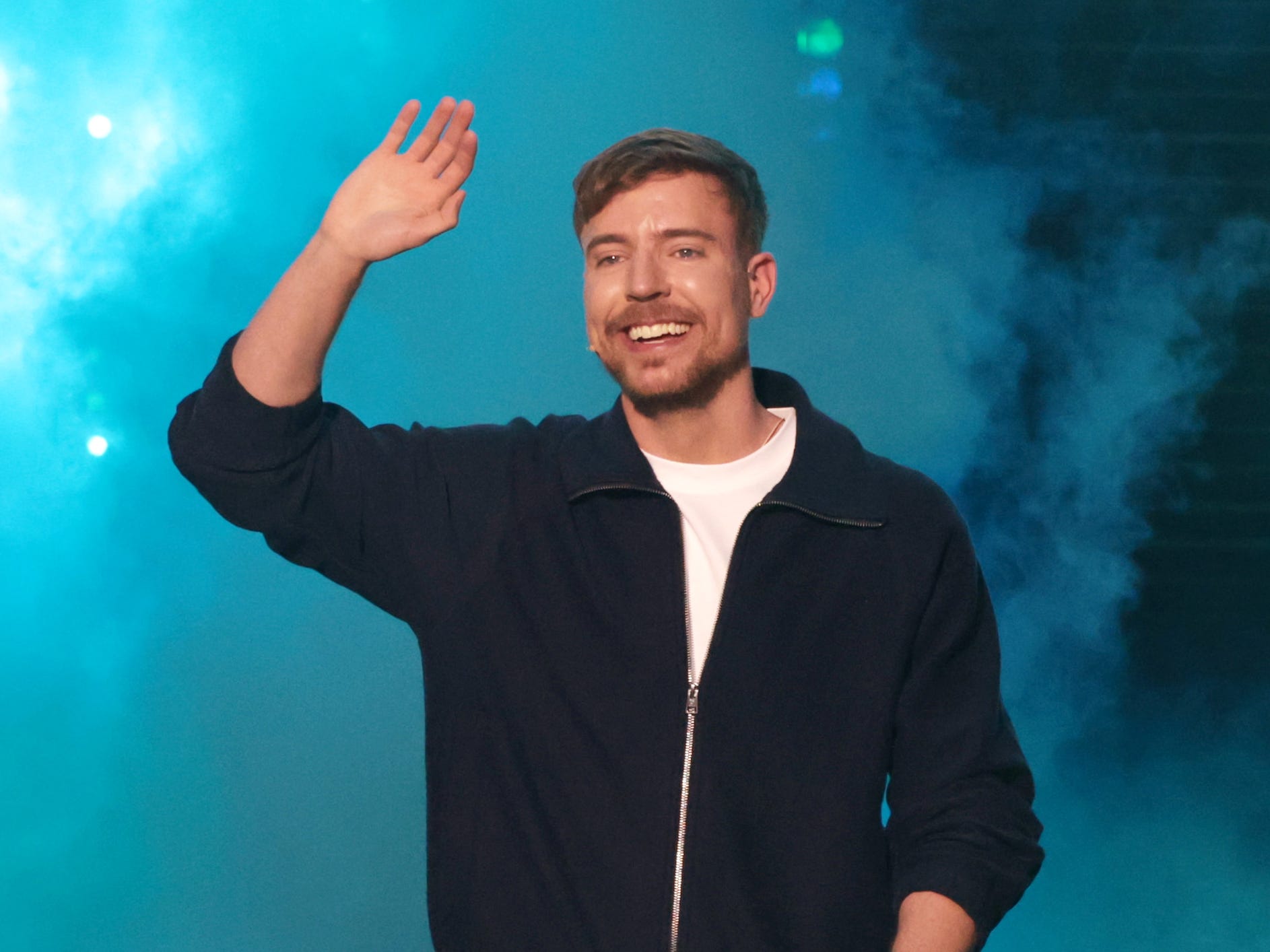 MrBeast onstage at the YouTube BrandCast, with a blue smokey background.