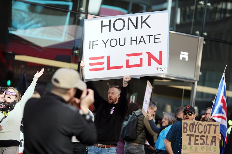 LONDON, ENGLAND - APRIL 5: Demonstrators rally against Tesla CEO Elon Musk, US President Donald Trump and their recent policies outside a Tesla showroom on April 05, 2025 in London, England. The London 'Hands Off' action group says that Donald Trump and Elon Musk think everything belongs to them and Londoners are fighting back! US citizens, Canadians, Brits, and people from all over the globe who've found a home in London are standing up for democracy. They believe that the US is threatening to invade Canada, Greenland, and Panama and are protesting as the Hands Off group in response. (Photo by Alishia Abodunde/Getty Images)