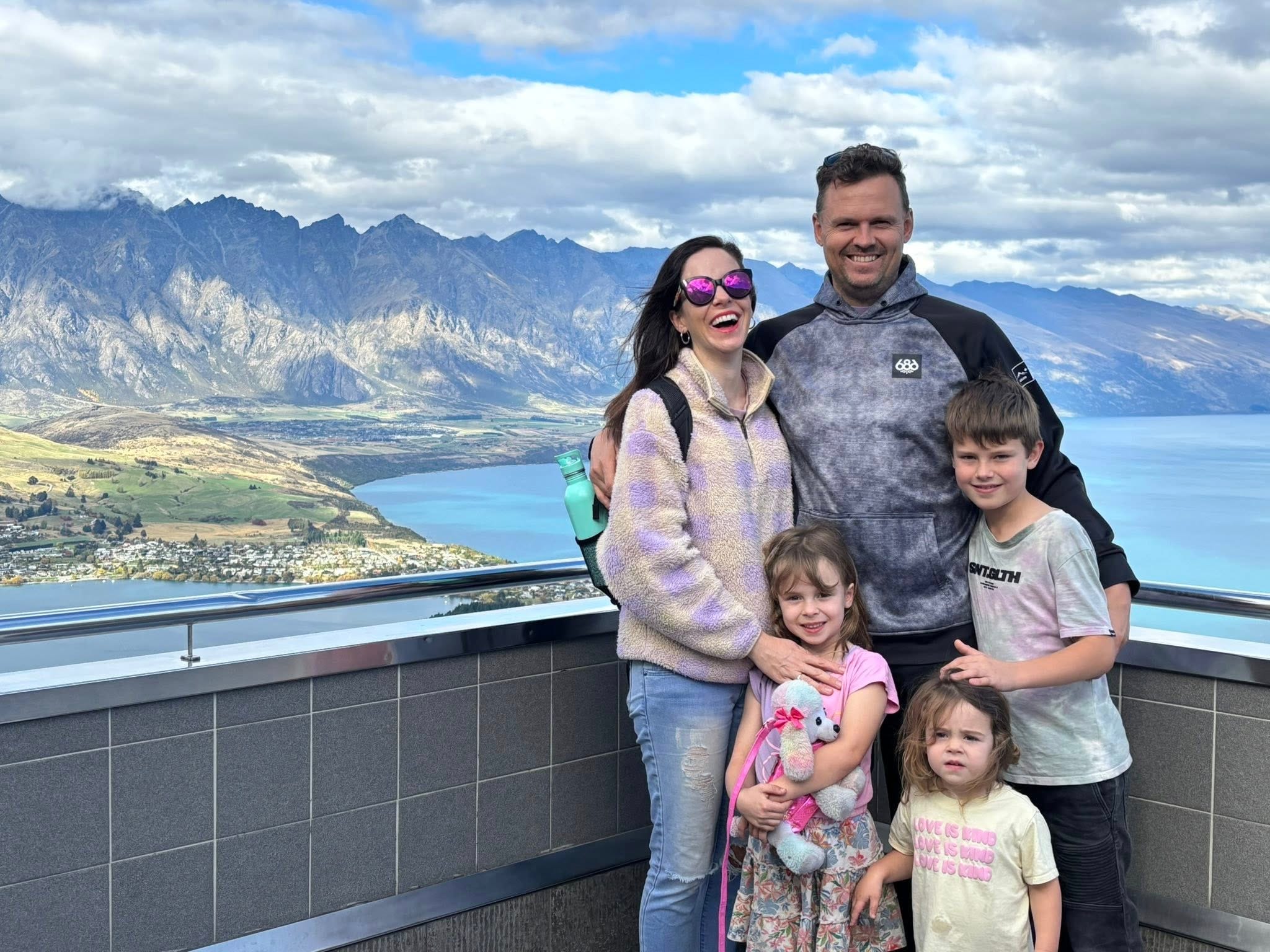 The author and her family in Queenstown standing on a balcony overlooking a body of water.