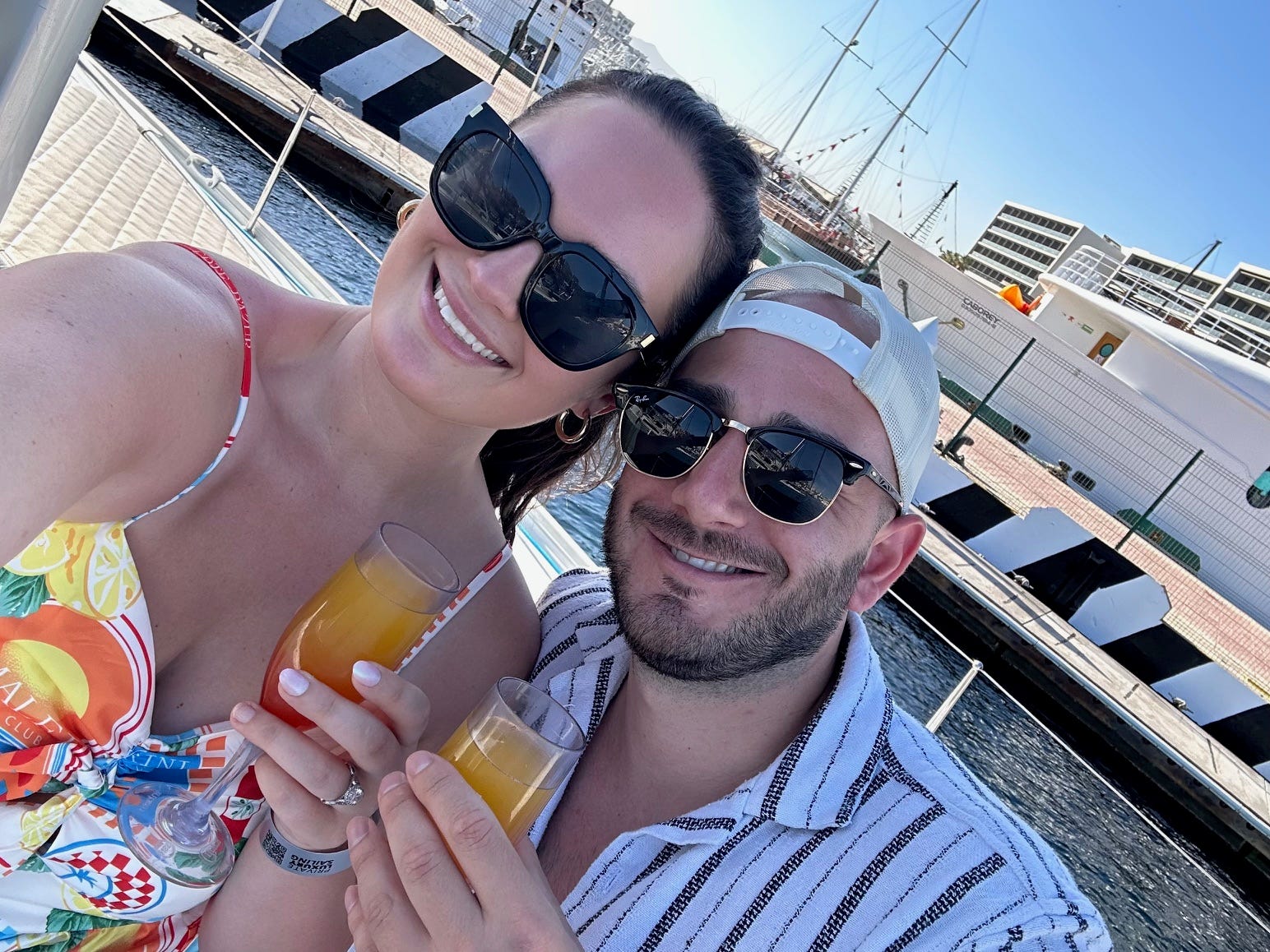 Author Hayley Hutson and her partner holding drinks on sailboat in Cabo