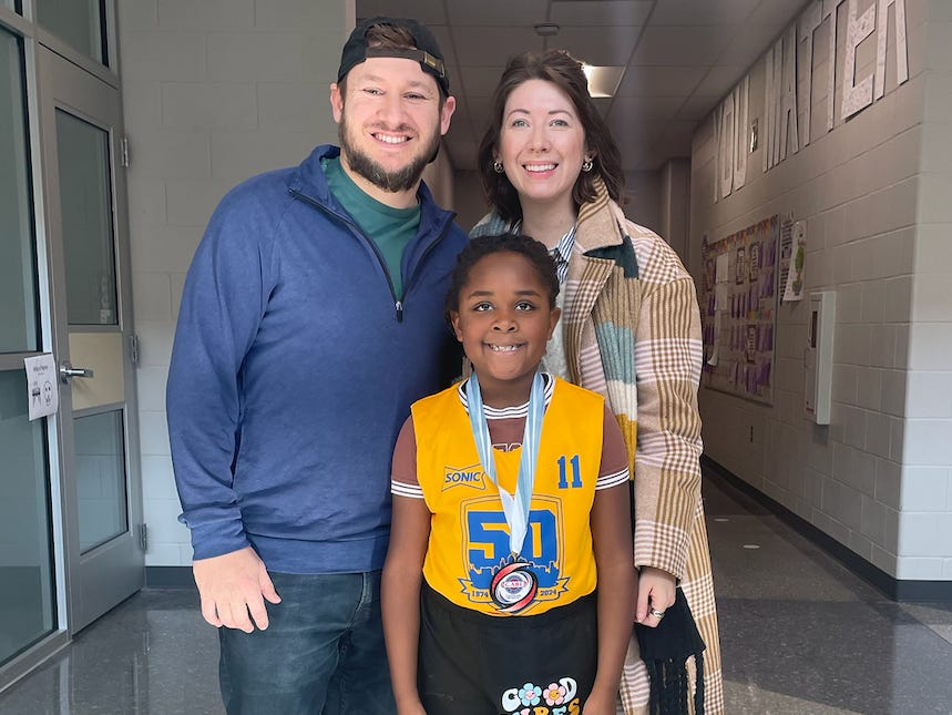 Emylee Williams, her husband, and her daughter wearing a sports medal
