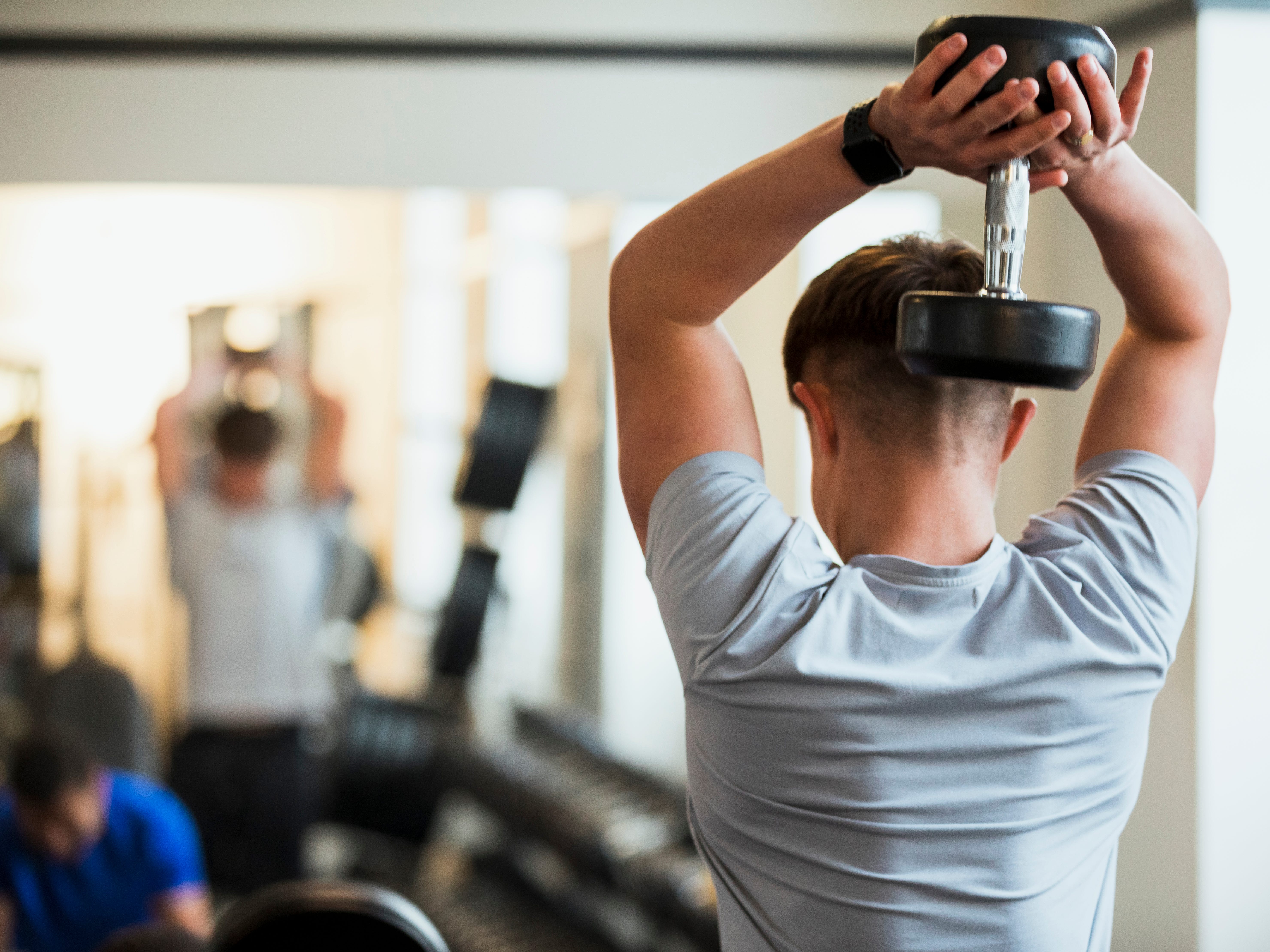 a teenager holding a dumbbell over his head