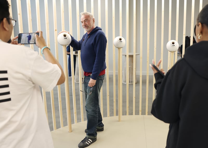 EL SEGUNDO, CA, MAY 2, 2025: Bernd Prager, of West Hollywood, center, gets his picture taken with an orb at the grand opening event of World, a company co-founded by Sam Altman that uses orbs to scan eyes to help people distinguish humans from robots, at the World storefront in West Hollywood on Tuesday, May 6, 2025. (Christina House / Los Angeles Times via Getty Images)
