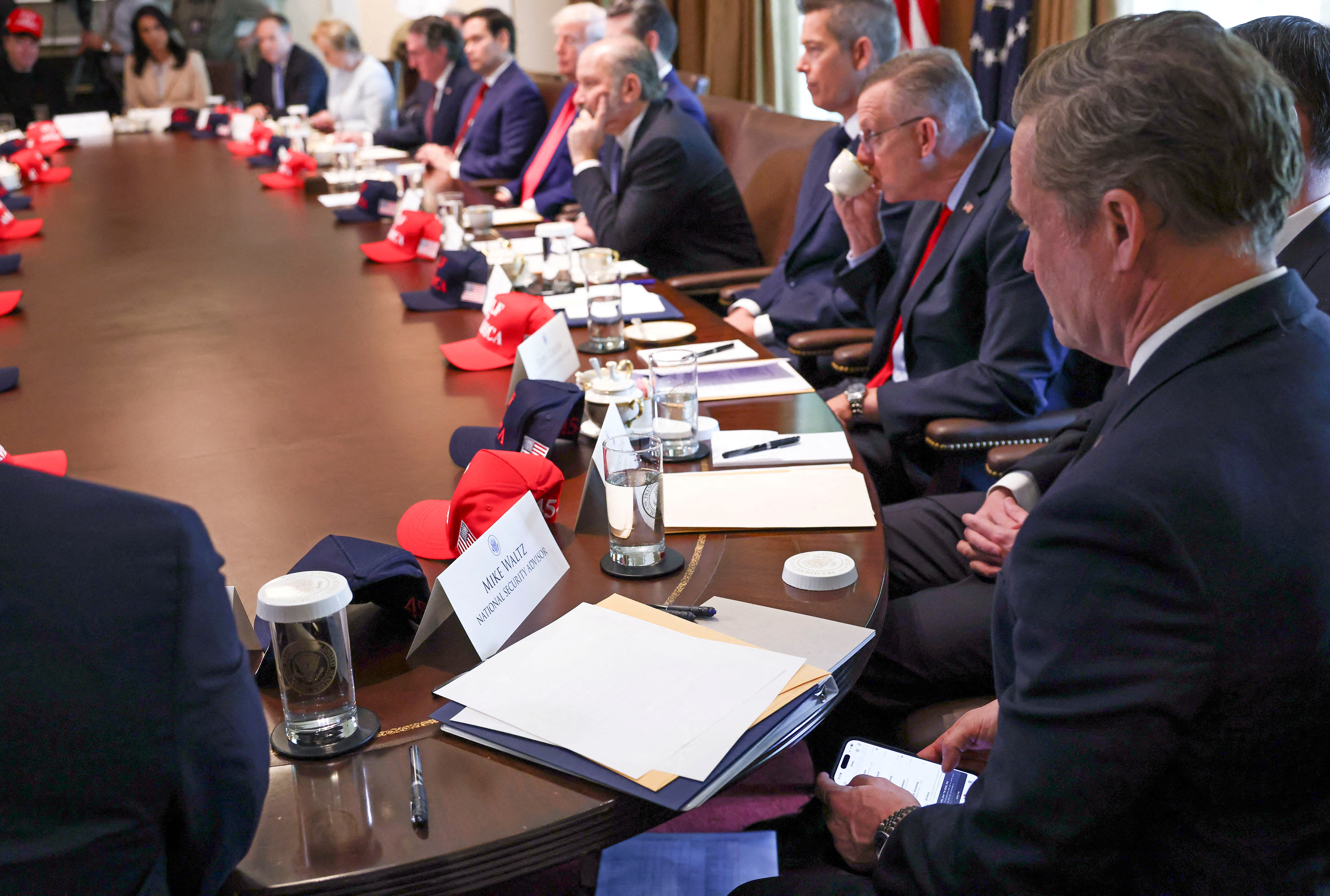 US national security advisor Mike Waltz checks his mobile phone while attending a cabinet meeting.