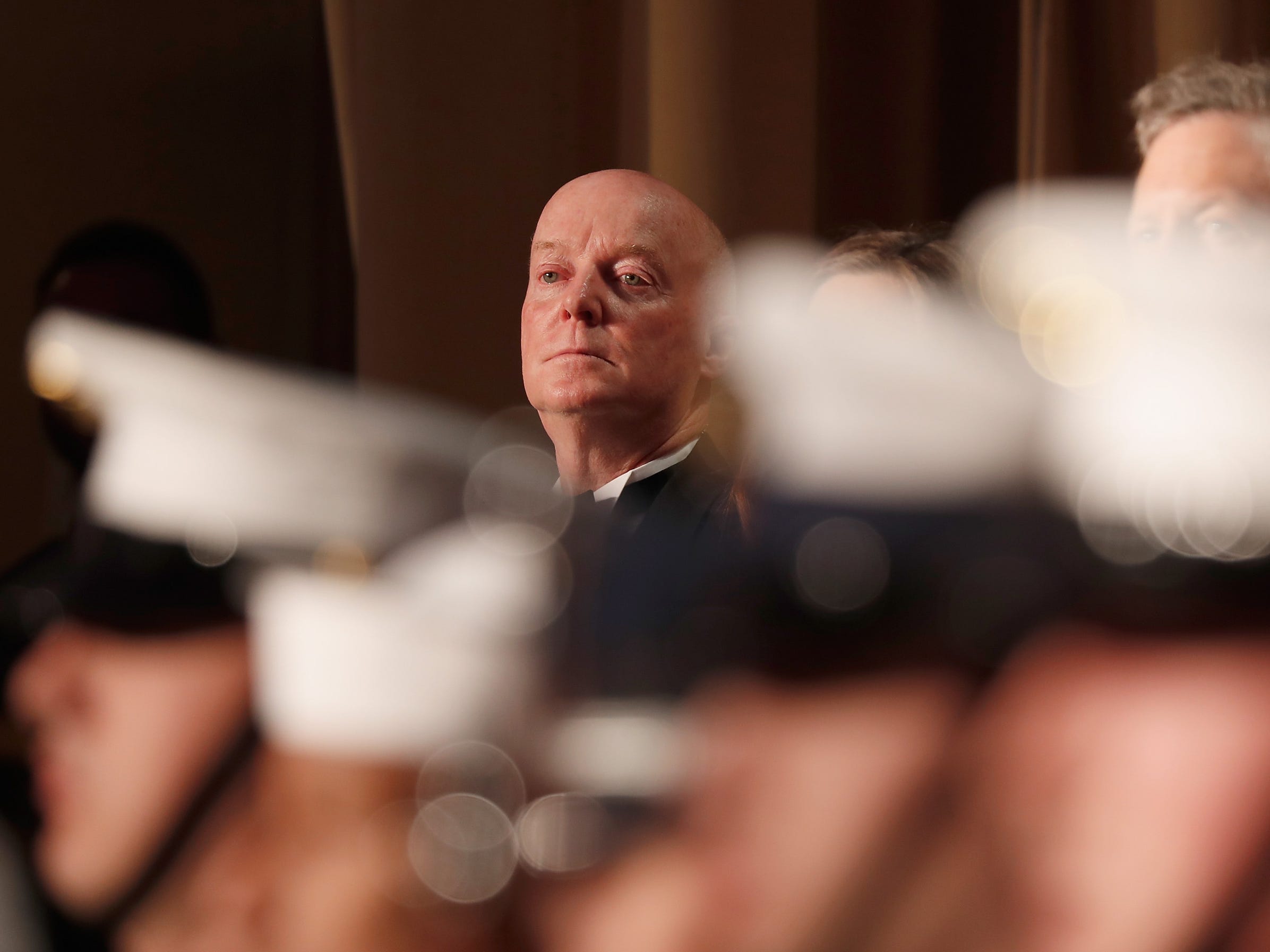 Doug Mills at the White House Correspondents dinner in 2018, with blurred out men in uniform in front of him.