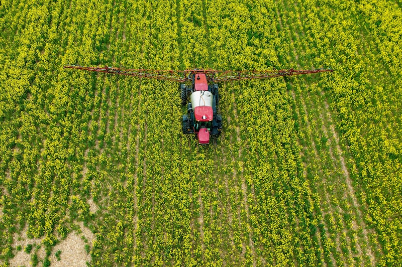 A farmer spreads pesticide on a field.