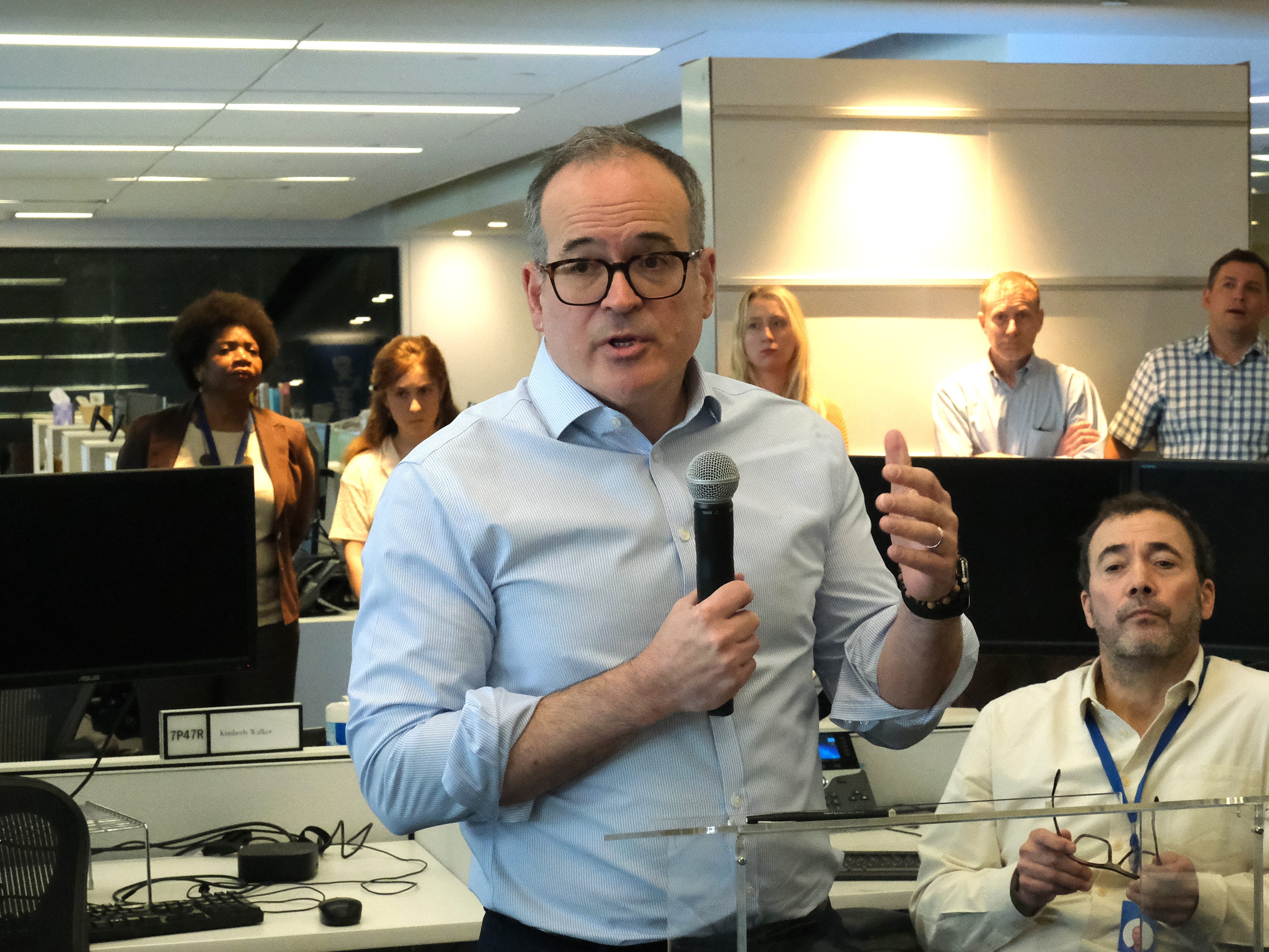 Matt Murray holding a microphone and speaking to the newsroom.