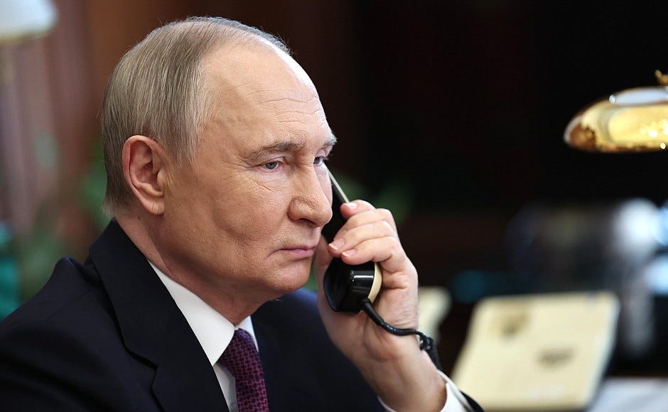 Vladimir Putin holds a phone to his left ear.