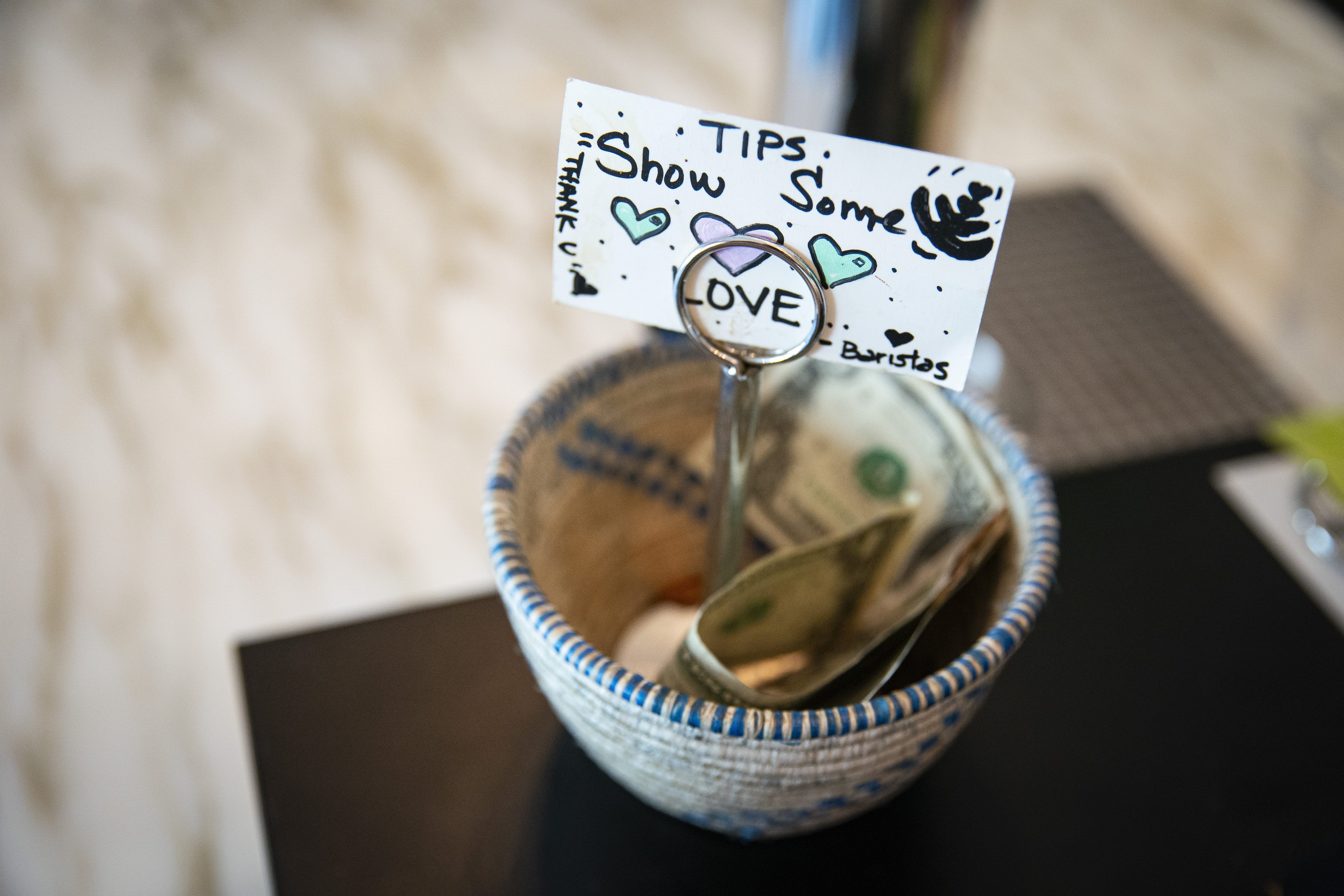 A sign on a tip bowl that says "Tips, show some love. - Baristas"