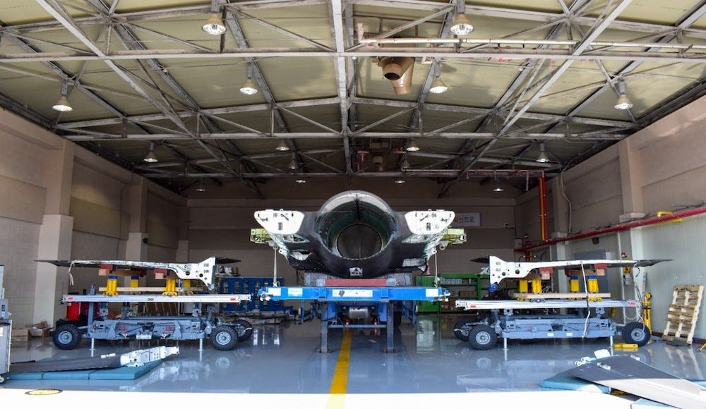 A front-on view of a Korean Air Force F-35A fighter jet which has been laterally bisected and both wings removed, in a hangar. The unattached wings are either side.