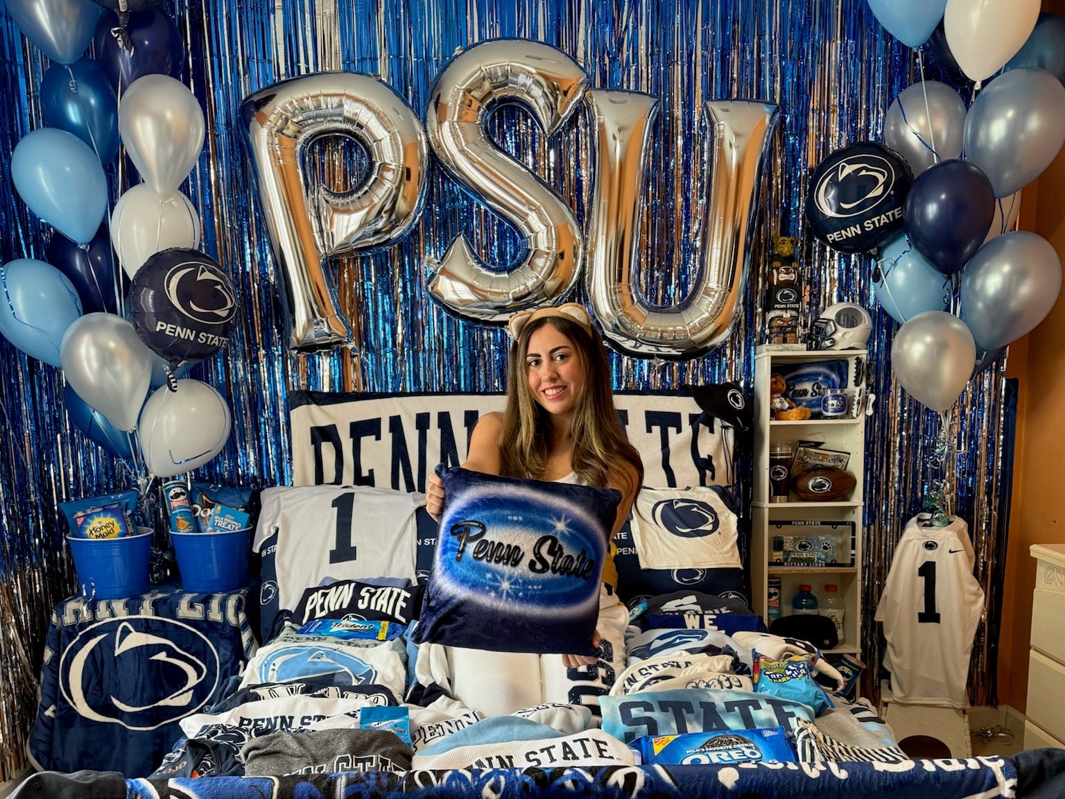 Mia Silverman sitting on her bed with PSU bed party theme decor.