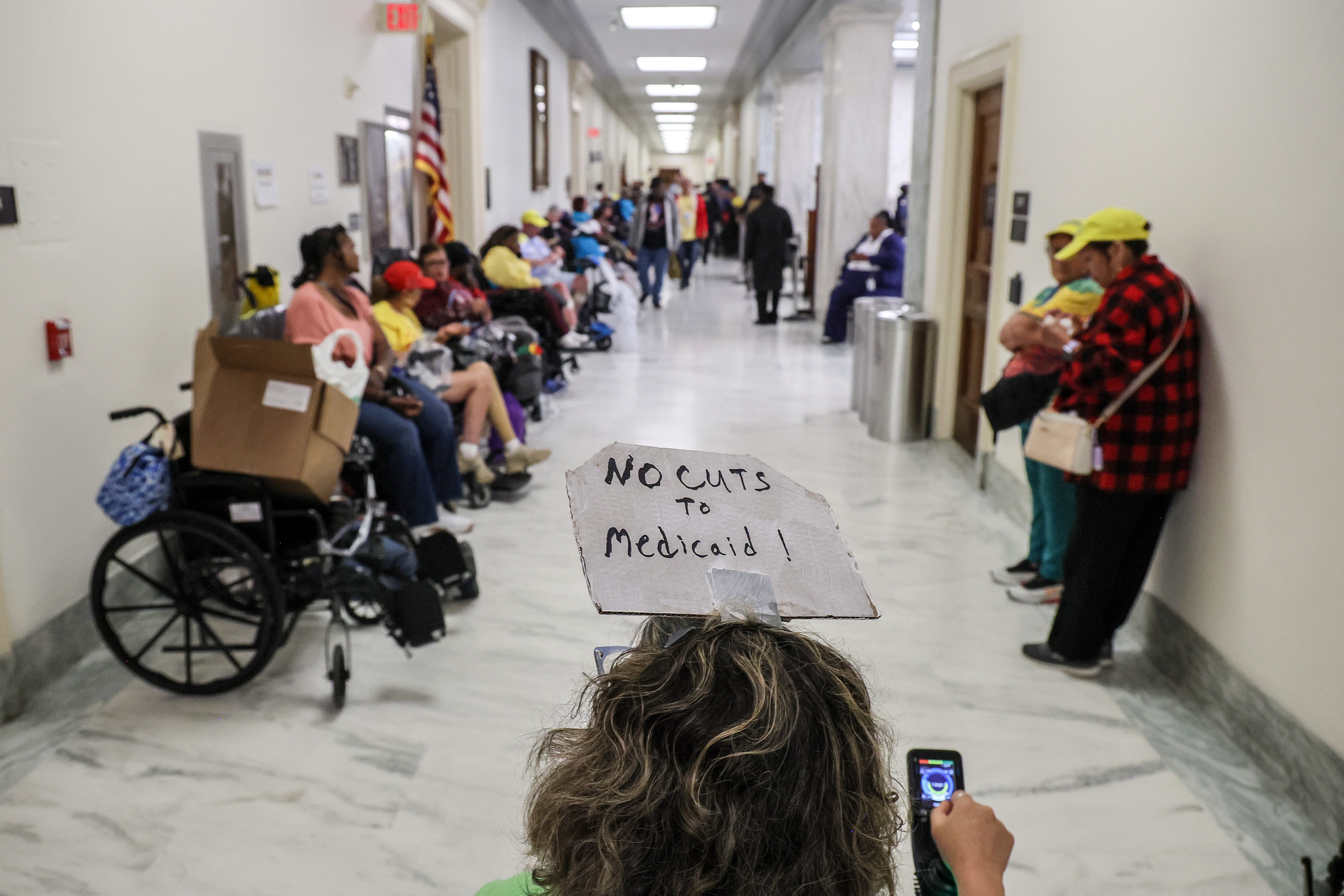 a protester in a wheelchair with a sign that says no cuts to medicaid