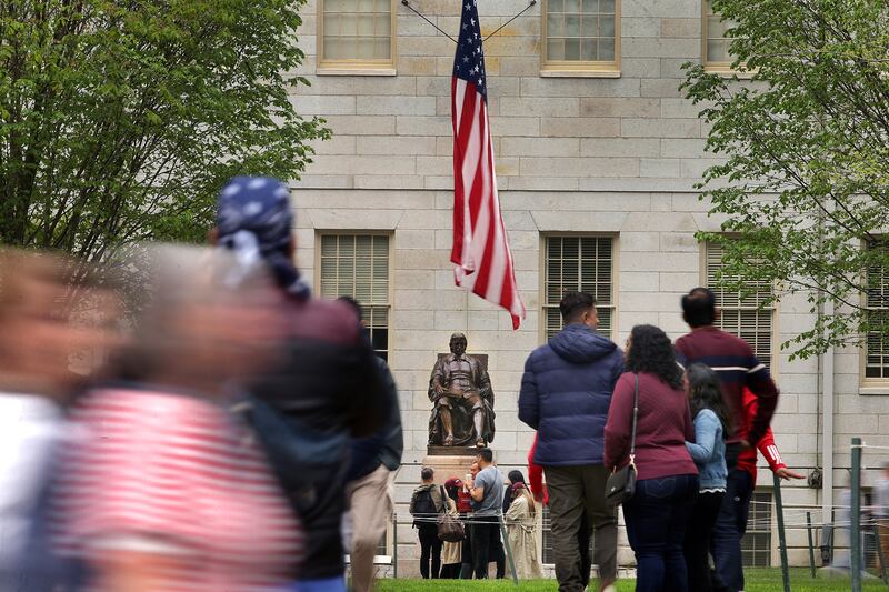 A Tour groups walk past the statue of John Harvard in Harvard Yard on May 2, 2025.
