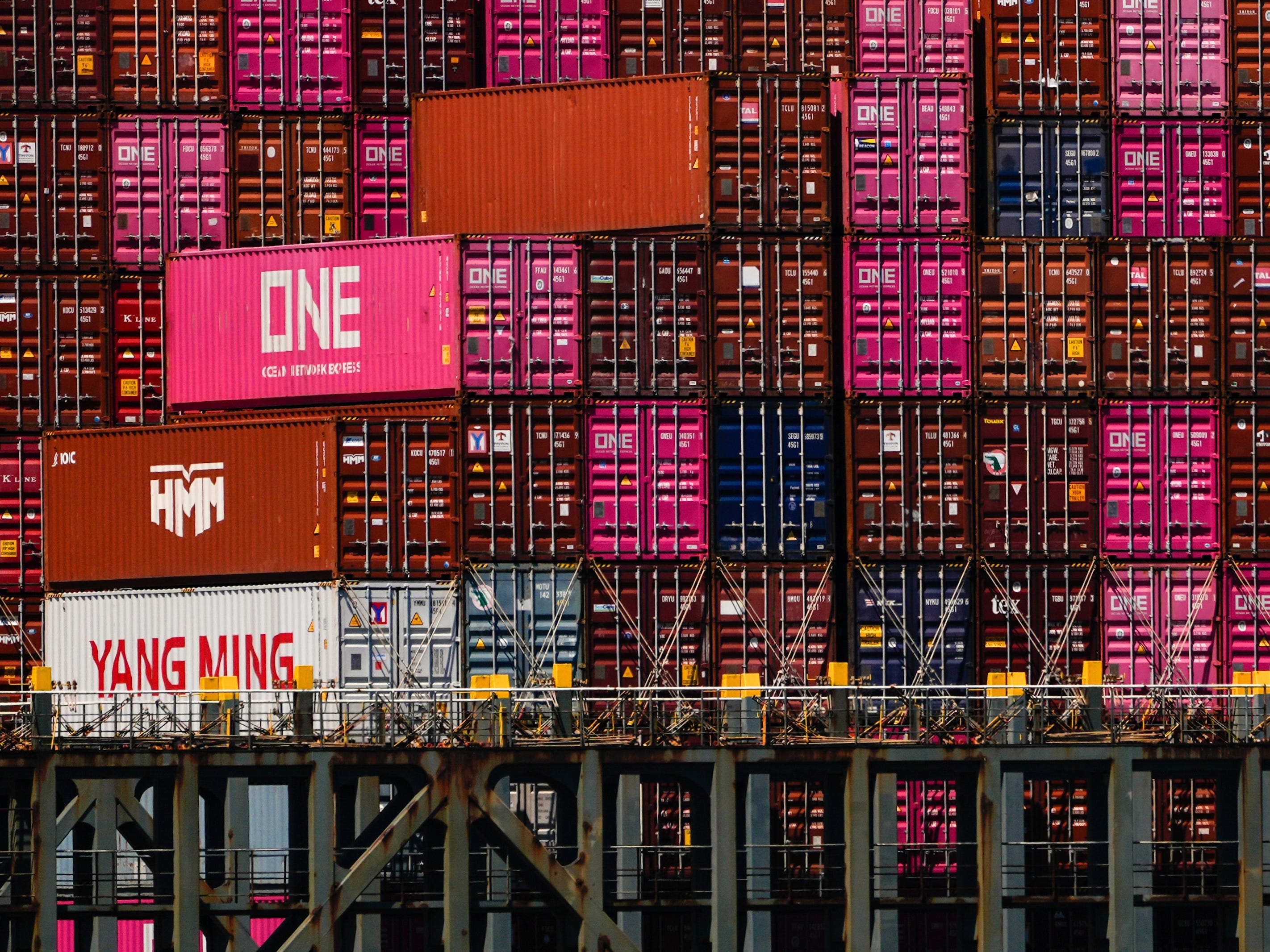 wall of pink and red shipping containers behind a dock