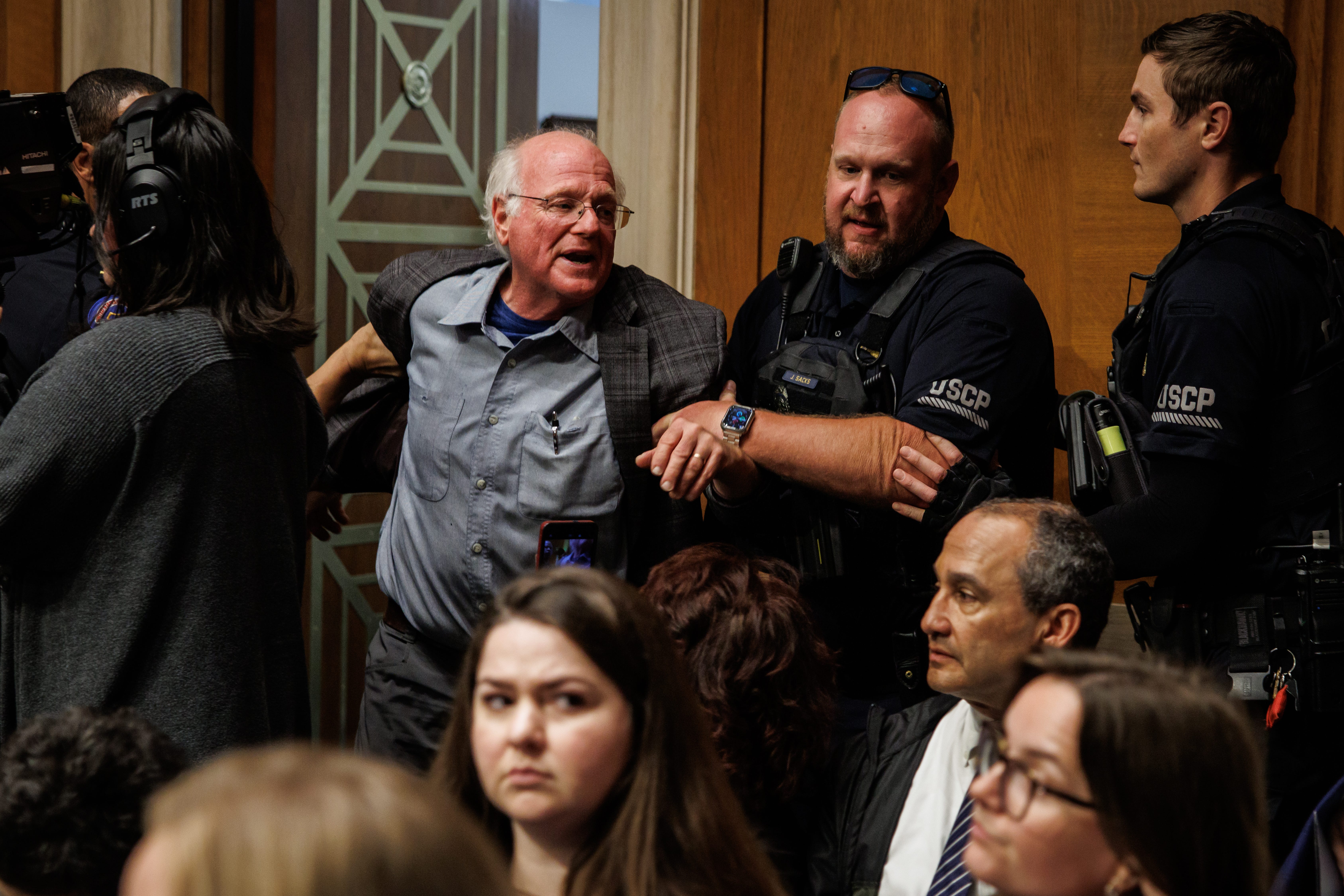 Ben Cohen being pulled out of his seat and out of the senate room by Capitol Police officers.