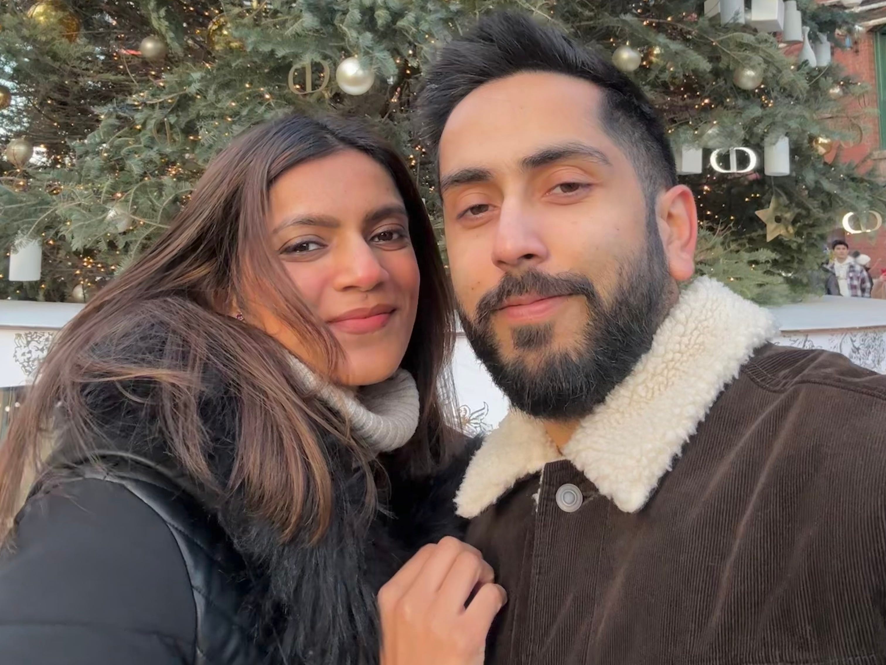 Vaishali Gauba with her husband stnading in front of a Christmas tree