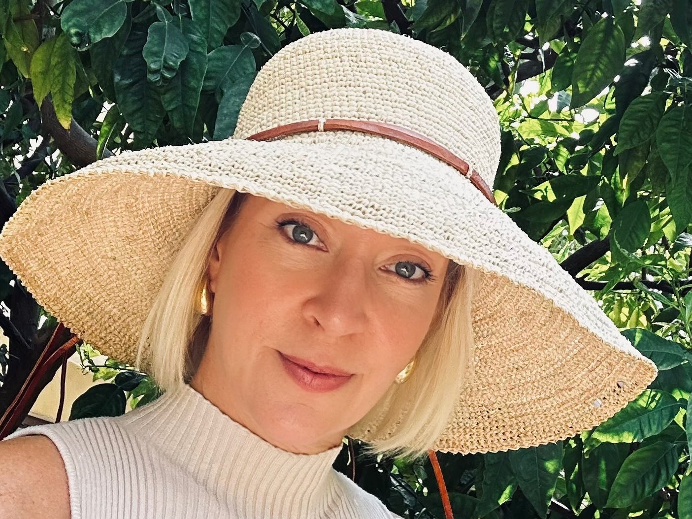 A woman with a sun hat and a sleeveless top.