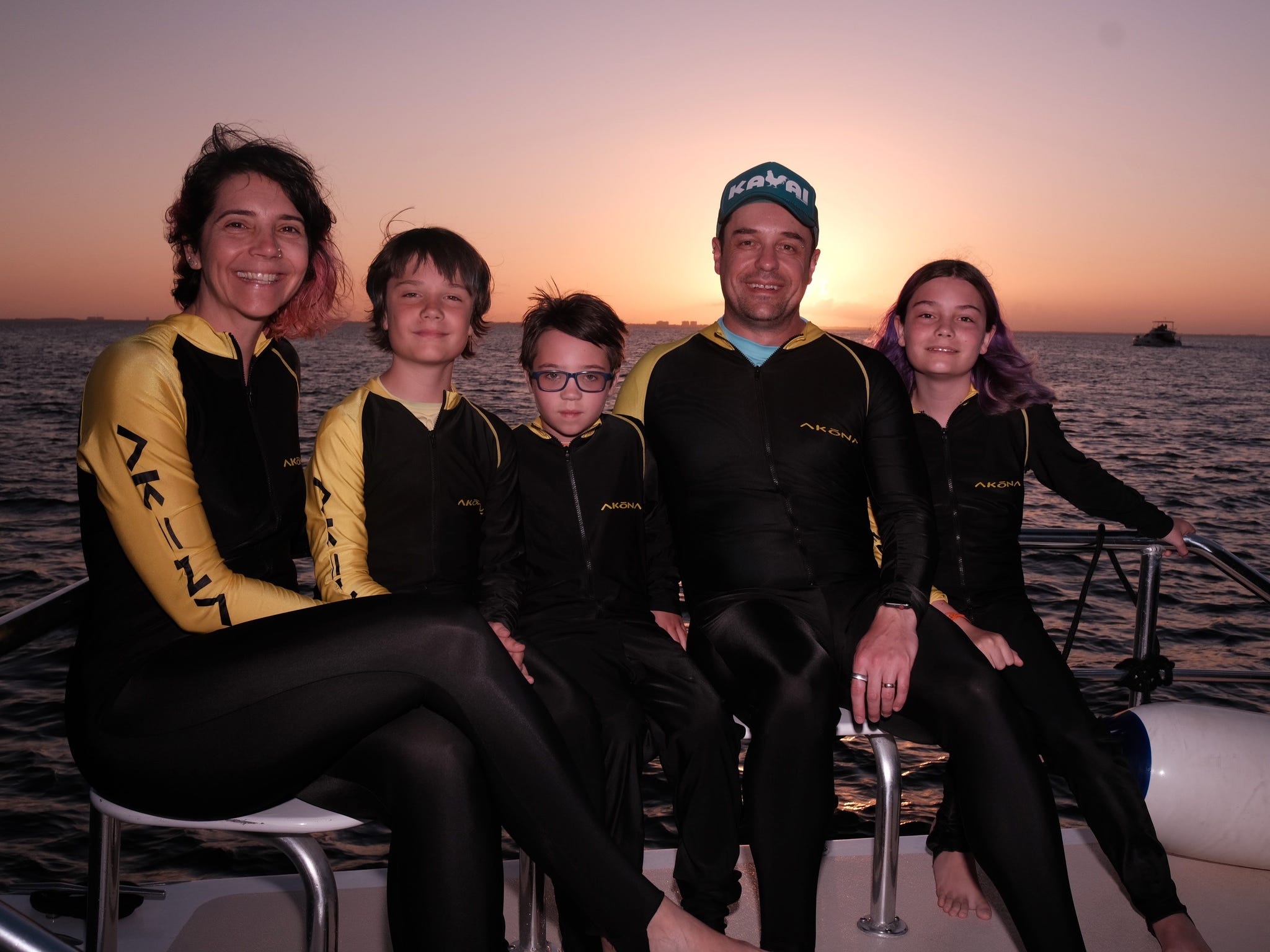 The author with her husband and three kids sitting on a boat at sunset