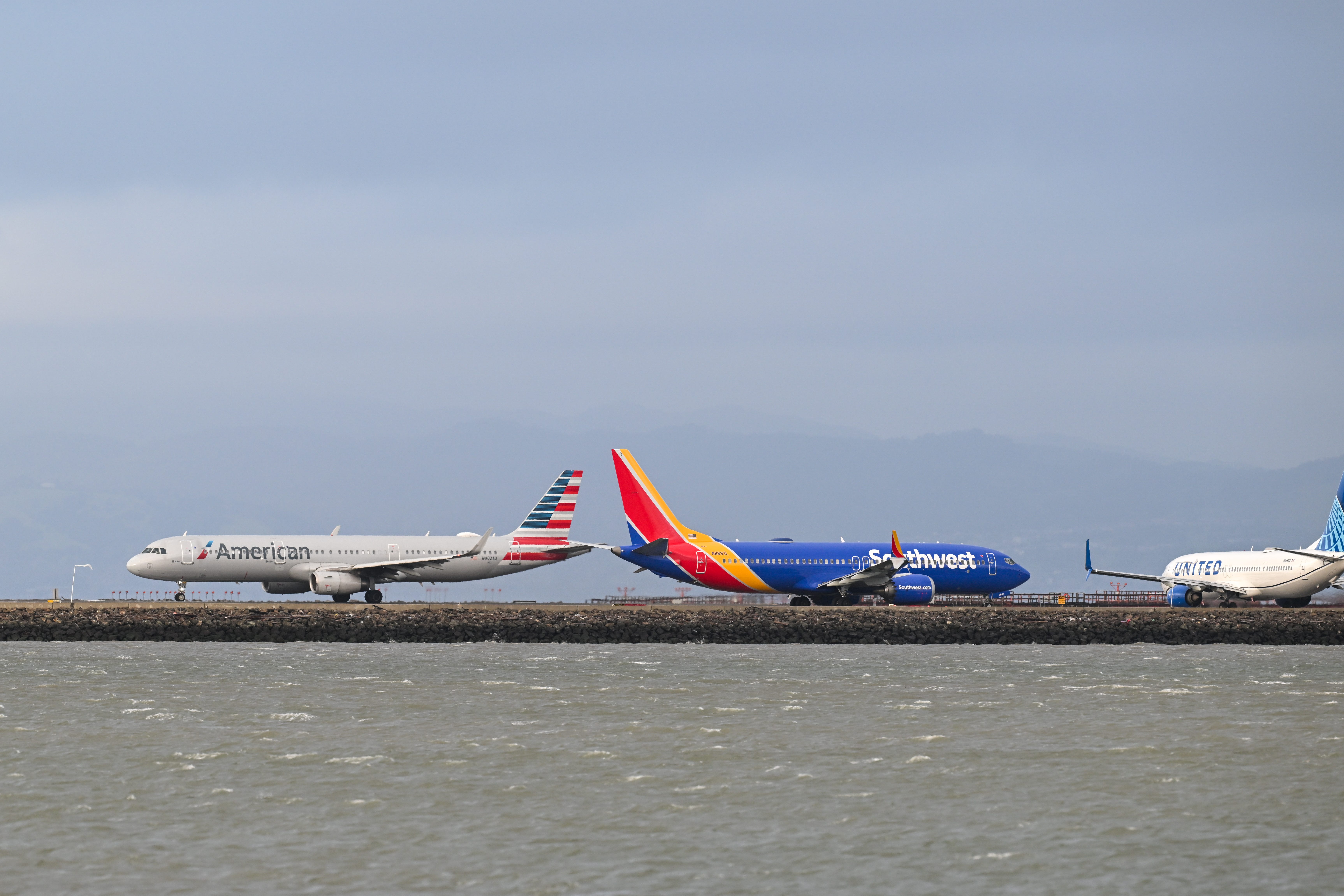 An American Airlines plane lands as a Southwest Airlines is taxiing to takeoff at San Francisco International Airport (SFO) in San Francisco, California, United States on March 17, 2025.
