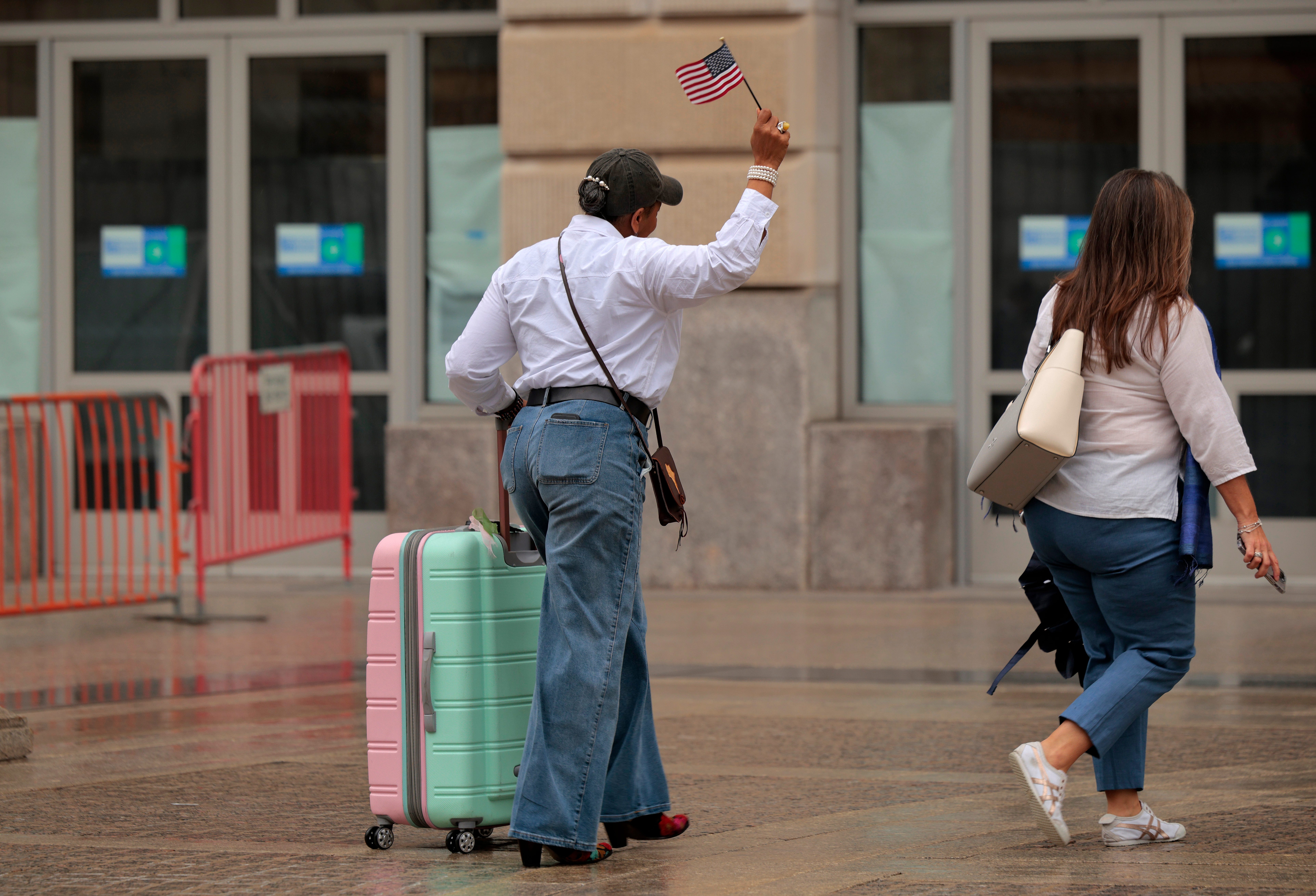 A woman with a suitcase holding an American flag